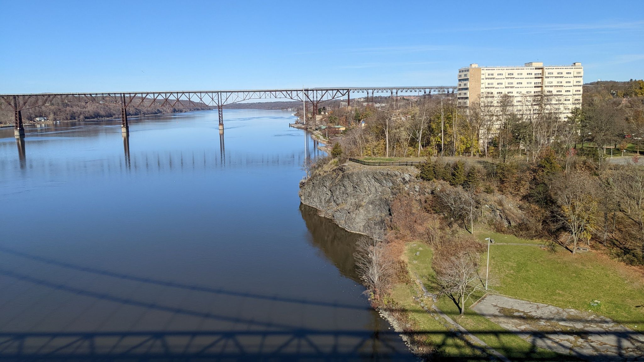 Truss bridge over a wide river with a rocky bank on a sunny day. - Franny Reese Park and Mid-Hudson Bridge Loop