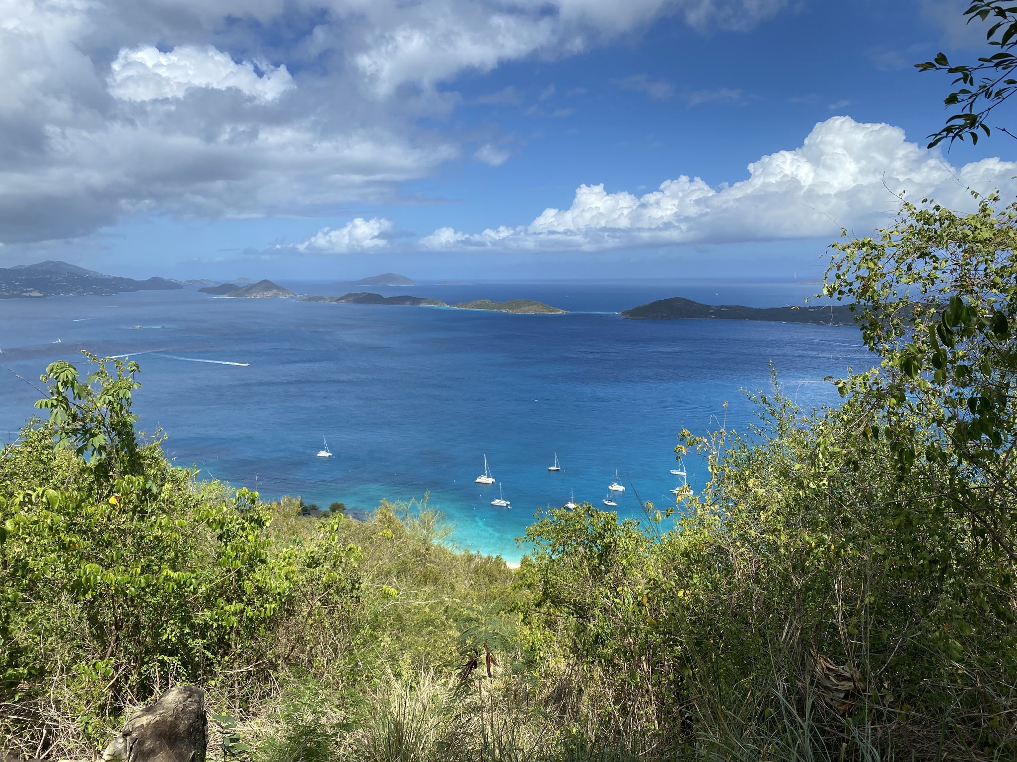 Vast blue ocean with distant islands and boats under a partly cloudy sky. - Caneel Hill Trail