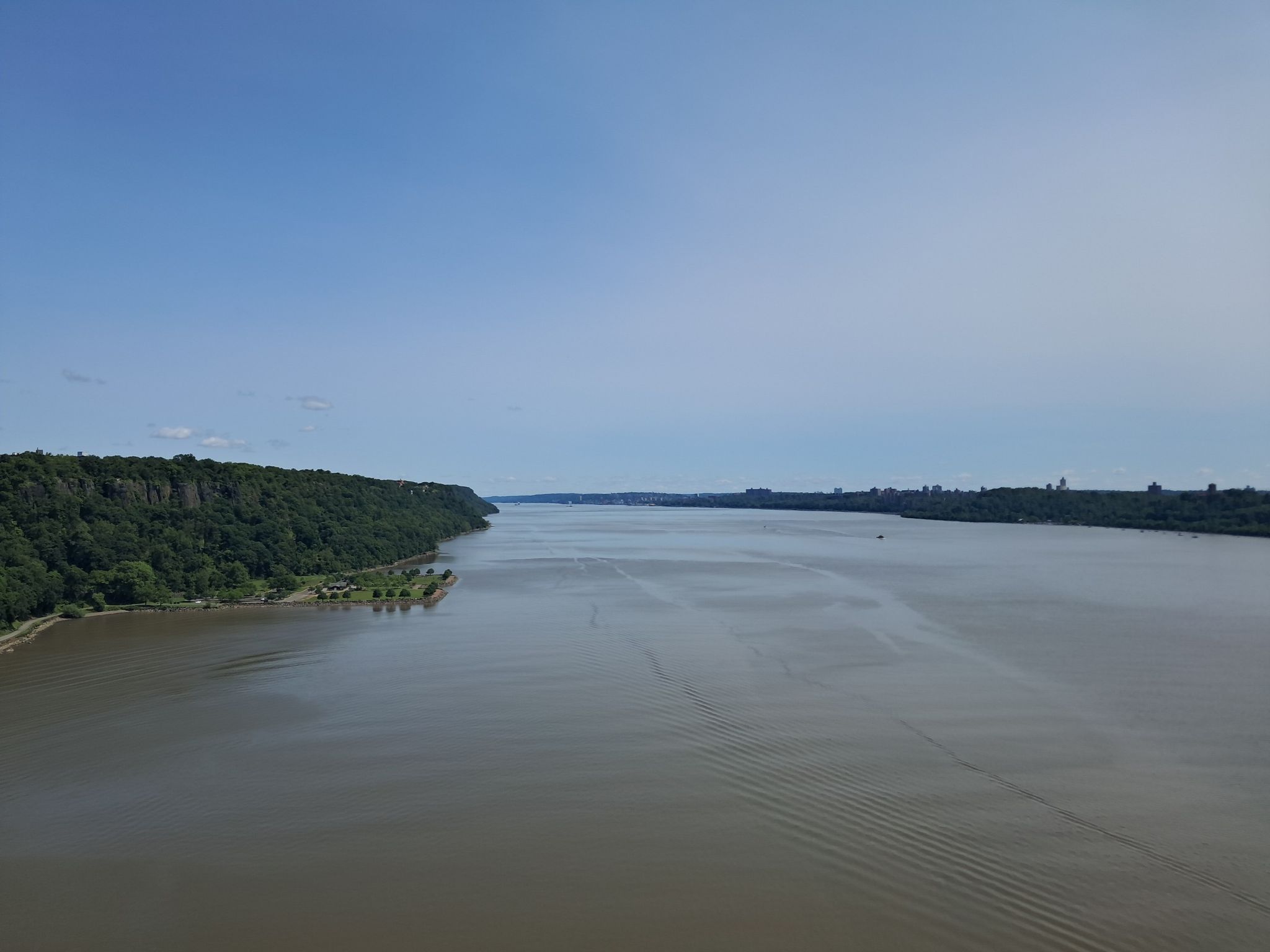 Expansive river with forested banks under a bright, clear blue sky. - Hudson River Greenway – Hudson River Greenway loop from 50th Street