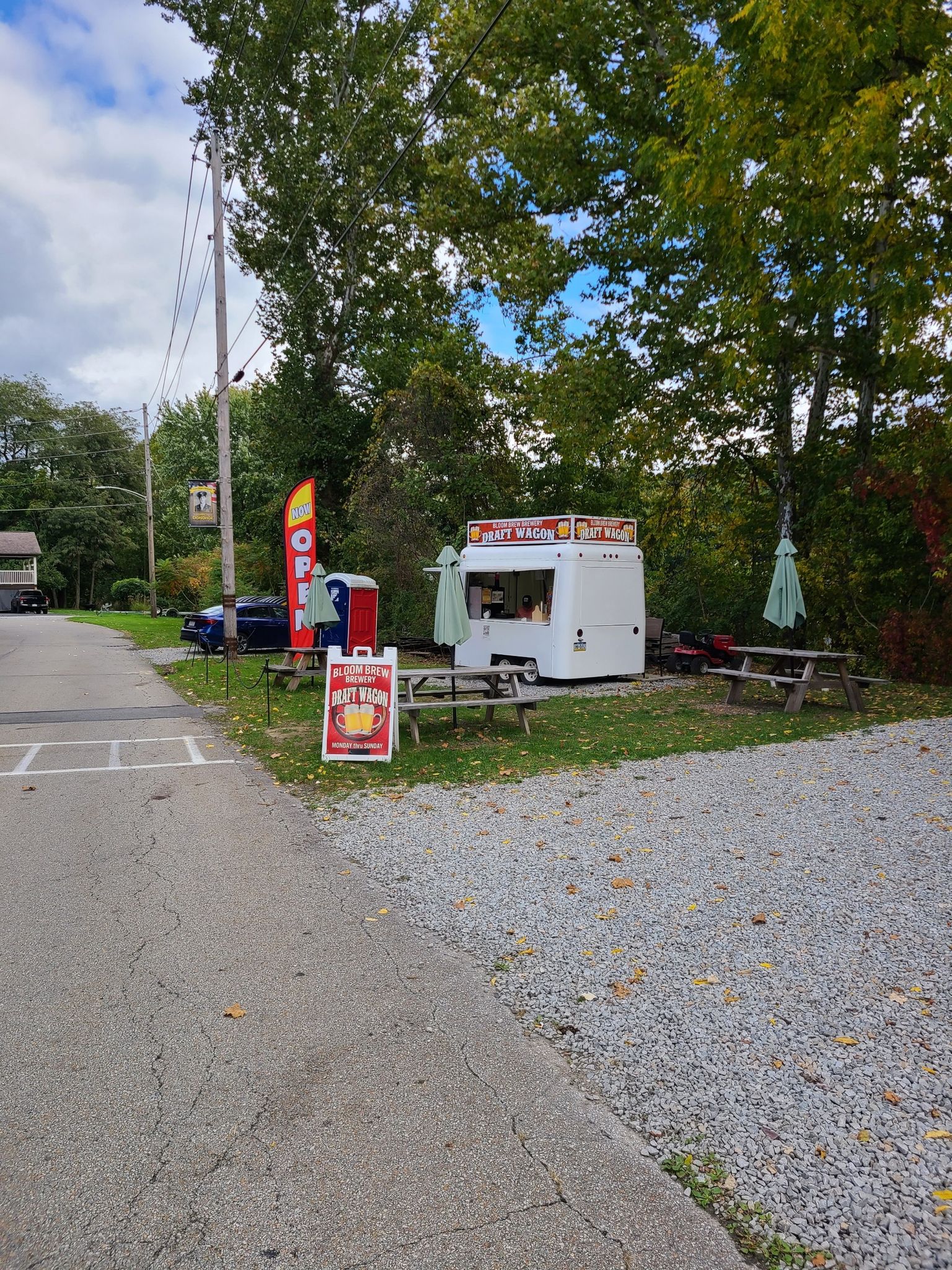 A white food truck with picnic tables and signs under trees on a bright day. - Great Allegheny Passage