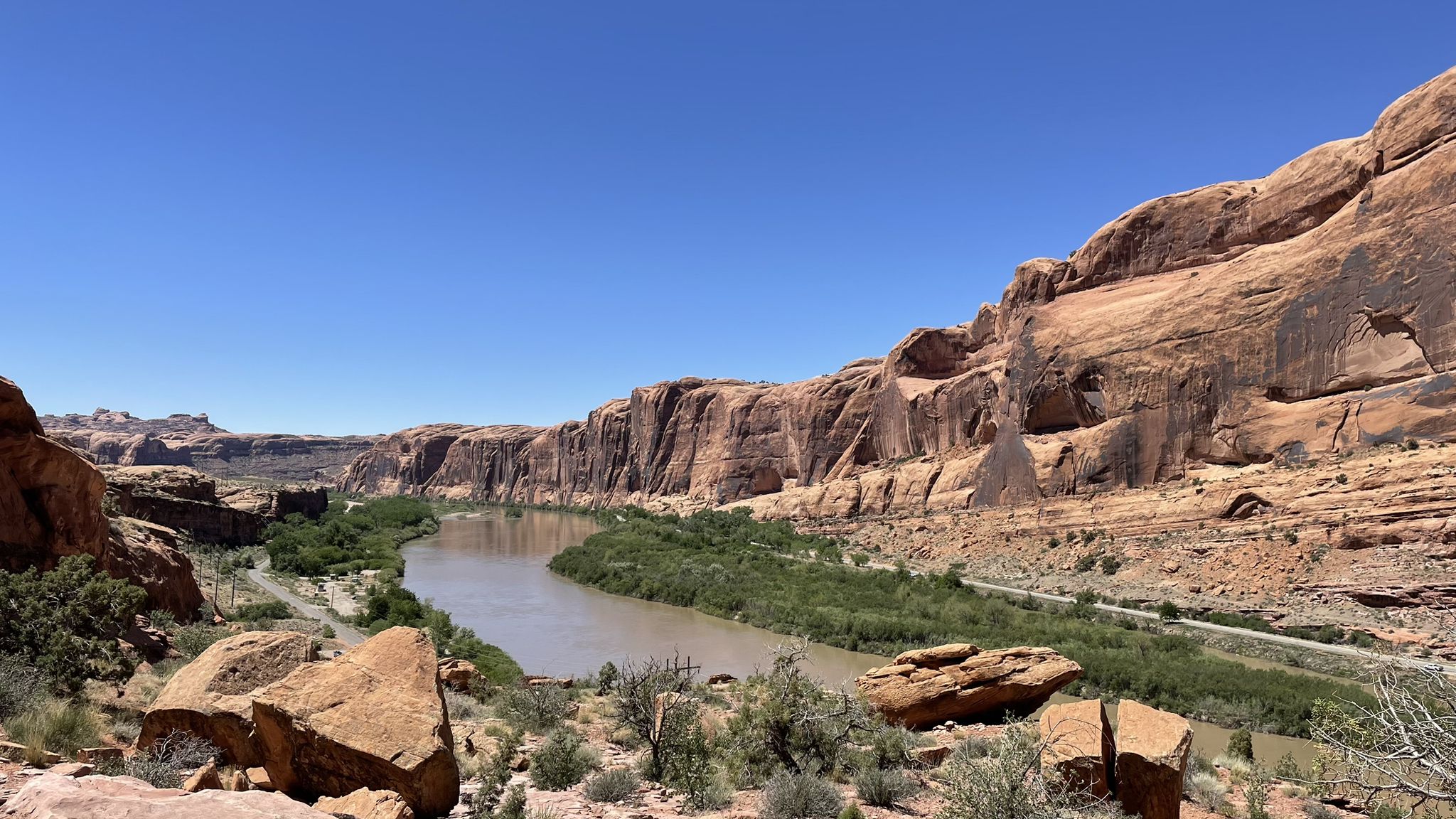 A wide river flows through a red rock canyon on a sunny day. - The Stairmaster – Moab Rim overlook loop from Scott Matheson Wetlands Preserve