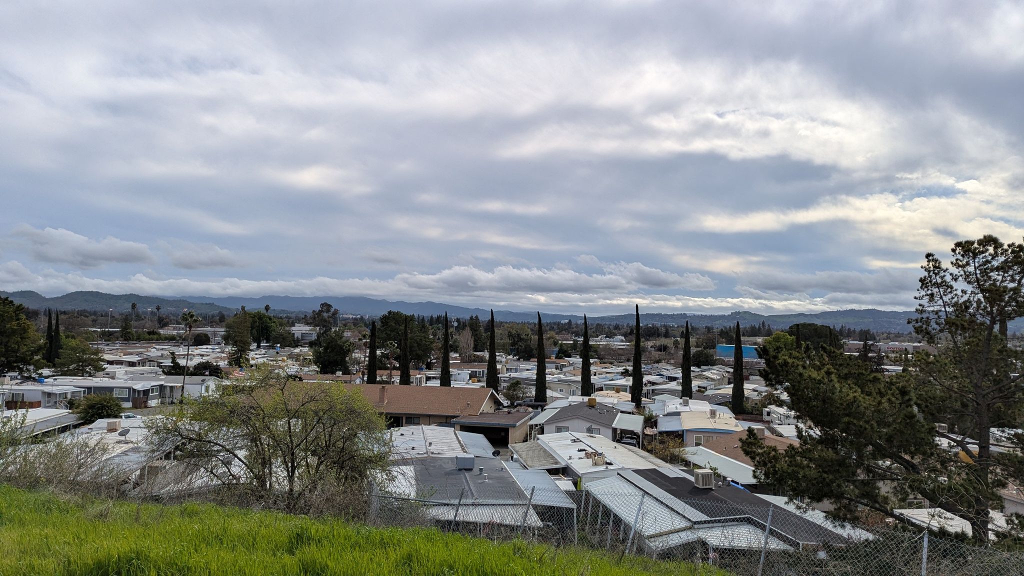Overcast view of a town with houses and tall trees, distant mountains. - Running loop from Concord