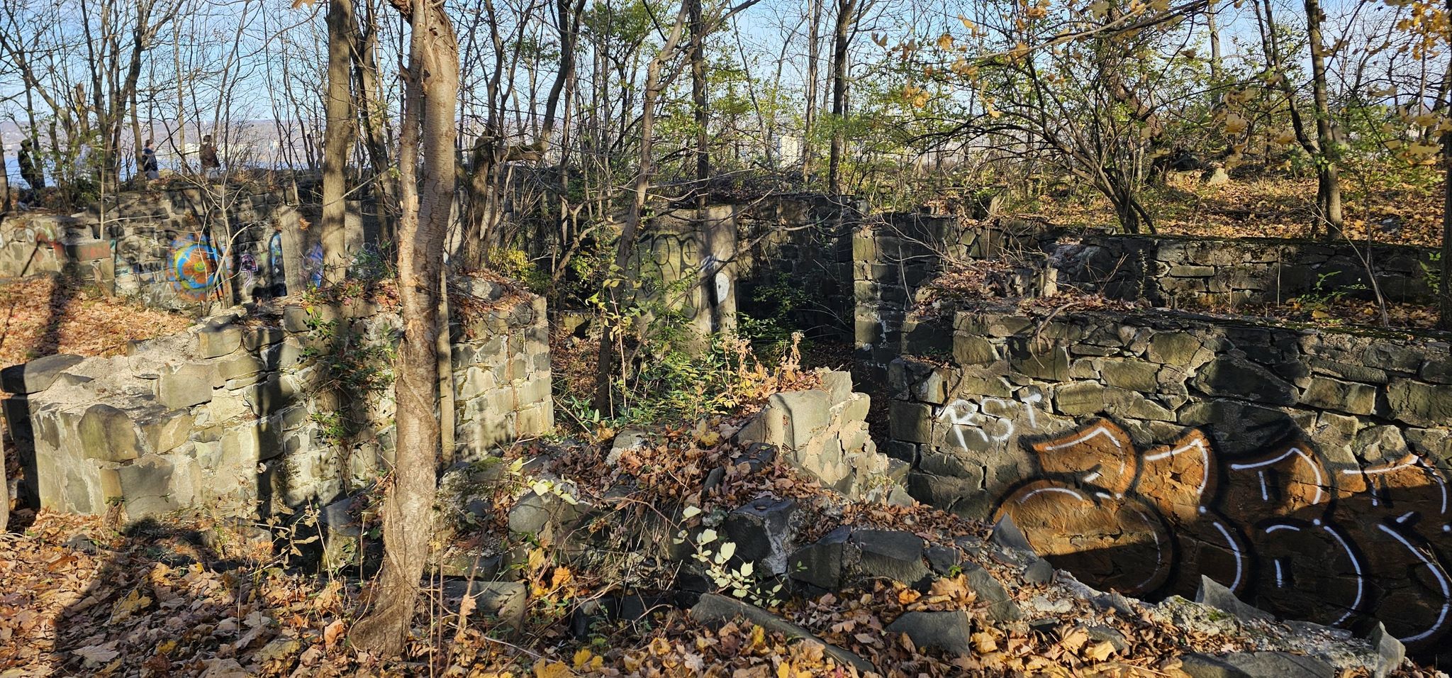Overgrown stone ruins with graffiti in a sunlit autumn forest. - Alpine Picnic Area loop from Alpine