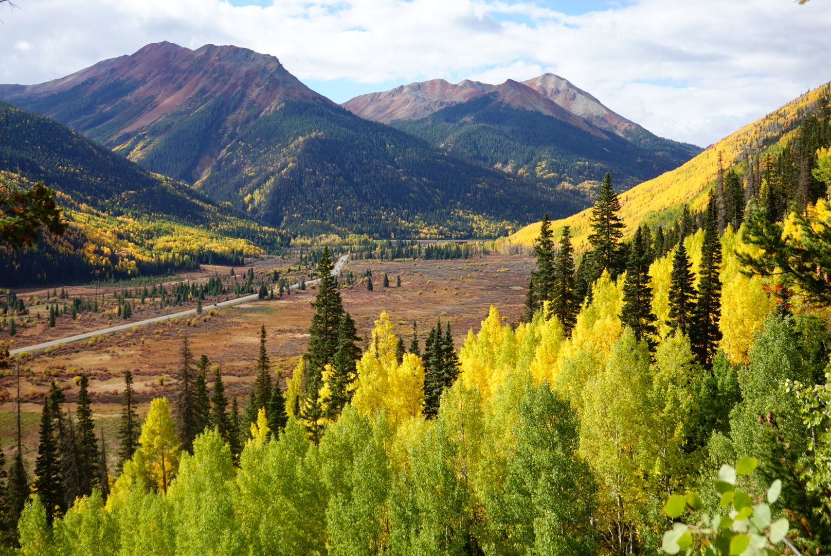 Bright autumn valley with colorful trees, mountains, and a winding road. - Mineral Creek OHV Trail