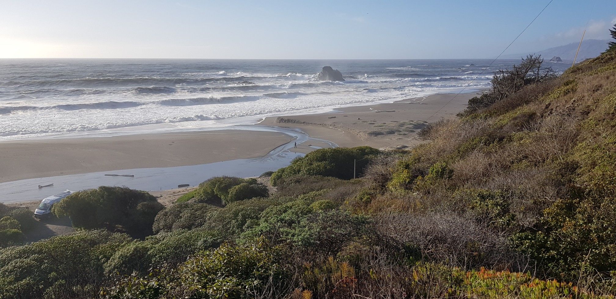 Panoramic view of a sunny beach with waves, a stream, and vegetated cliffs. - Goat Rock – Peaked Hill Viewpoint loop from Jenner
