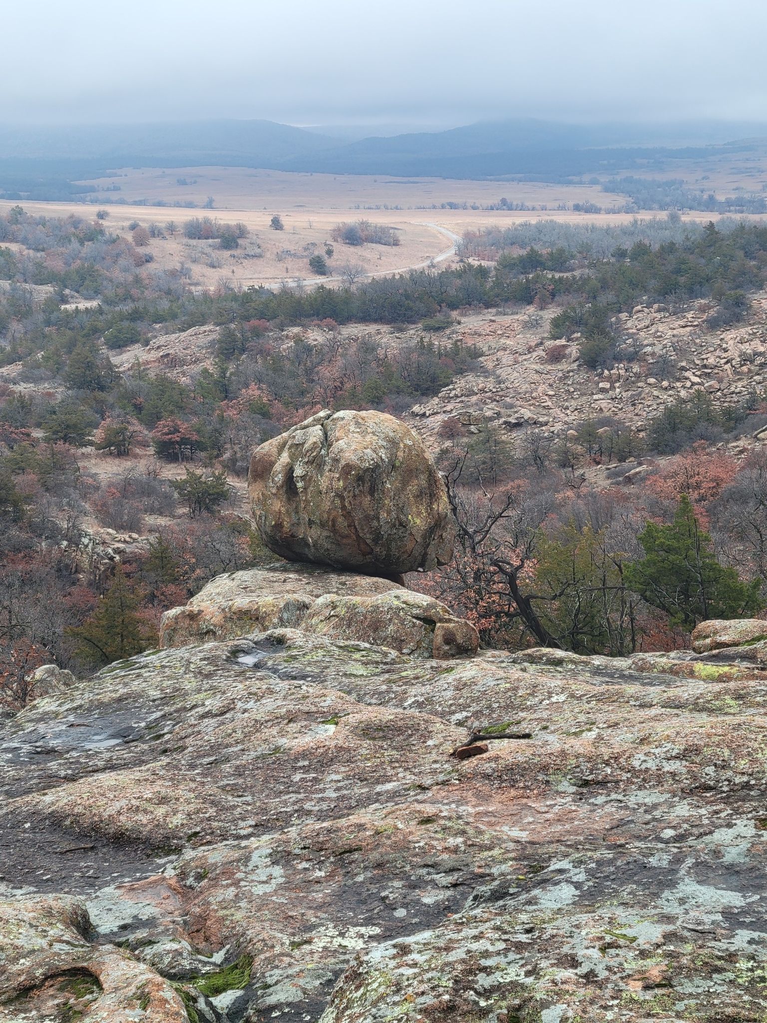 Large balanced boulder on a rocky hill overlooking a hazy valley. - Charon's Garden Trail