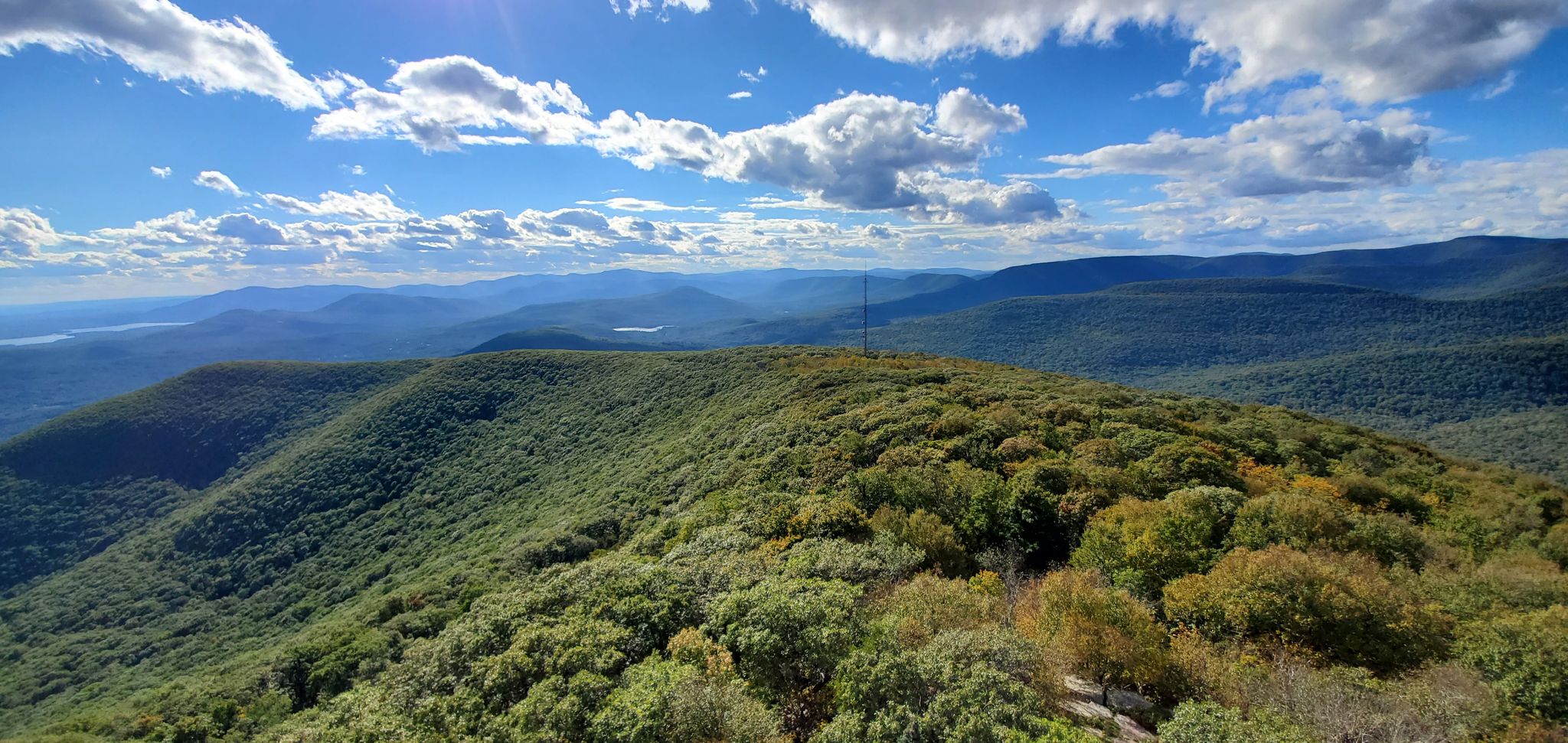 Panoramic view of green forested mountains under a bright, cloudy sky. - Overlook Spur Trail