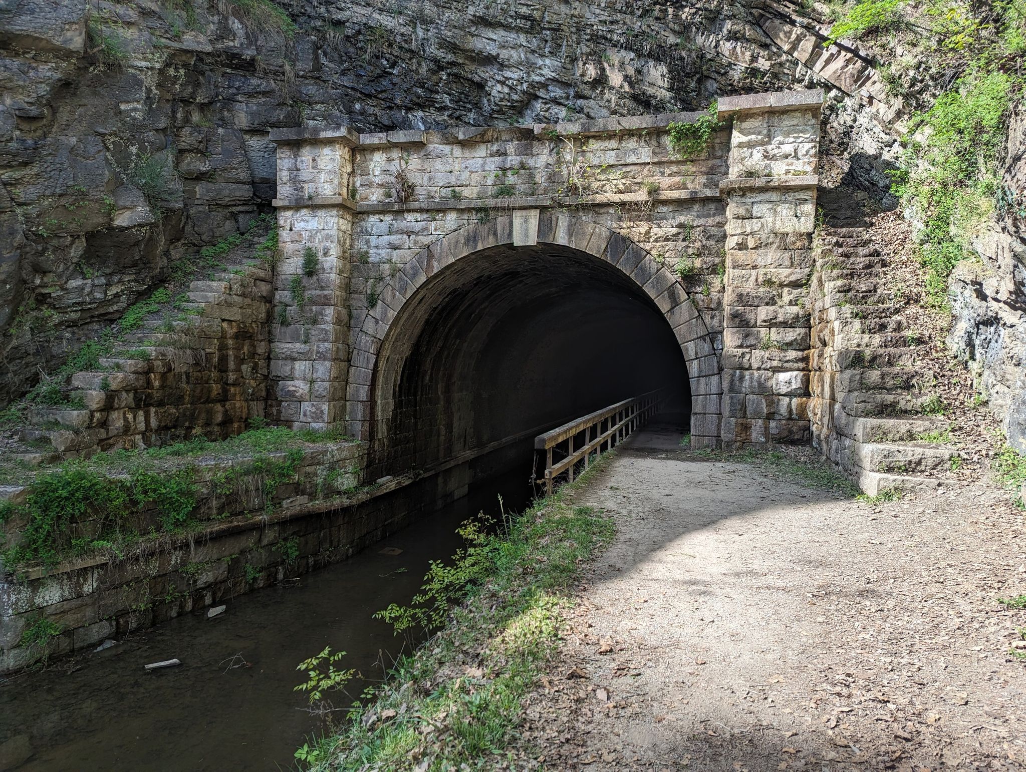Ornate stone tunnel entrance with a canal and dirt path beside rocky cliffs. - Paw Paw Tunnel – Paw Paw Tunnel loop from Paw Paw