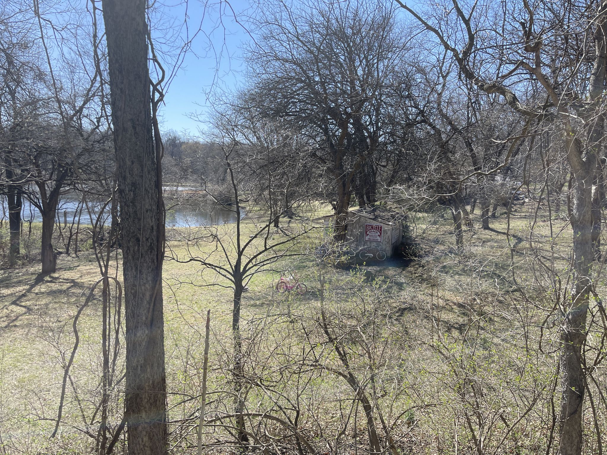 Small rustic building in a clearing with bare trees and water. - Rock Island Trail