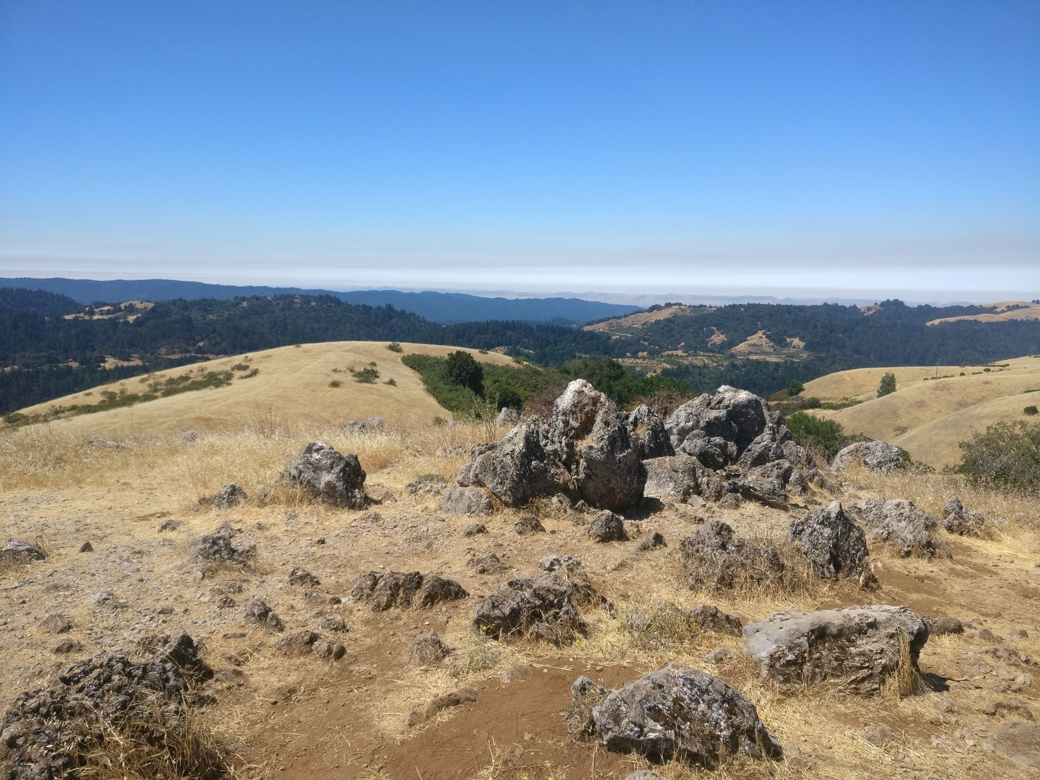 Rocky, dry hilltop with scattered boulders overlooking distant hills under clear sky. - Rancho San Antonio County Park – Black Mountain loop from Rancho San Antonio County Park