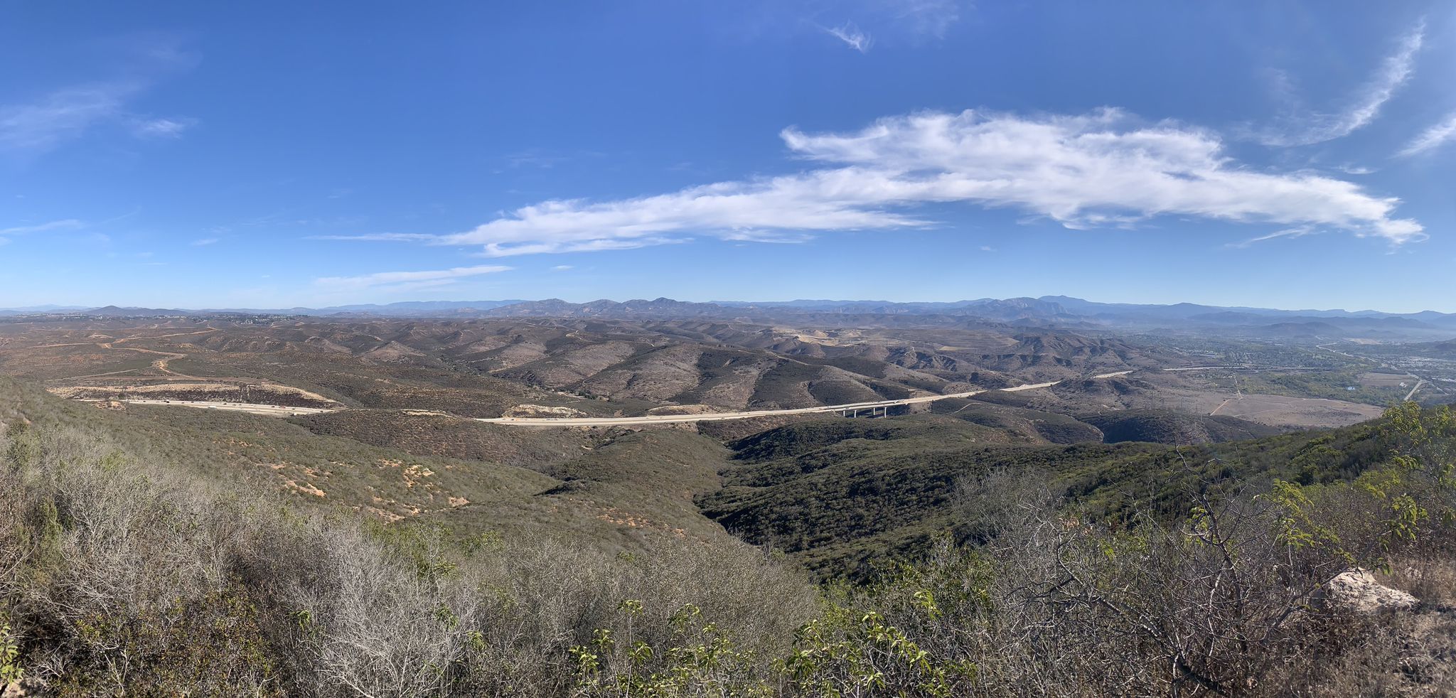 Panoramic view of rolling hills, a distant highway, and a bright blue sky. - Old Mission Dam – North Fortuna Summit loop from Mission Trails Regional Park
