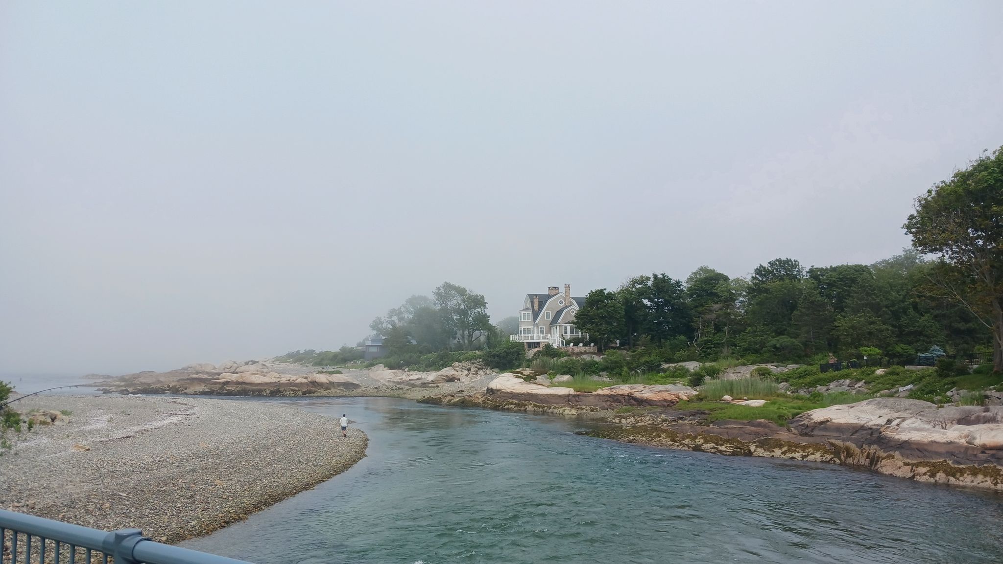 River flowing into the ocean past rocky shores and a house on a foggy day. - Sandy Beach loop from Breadencheese Conservation Area