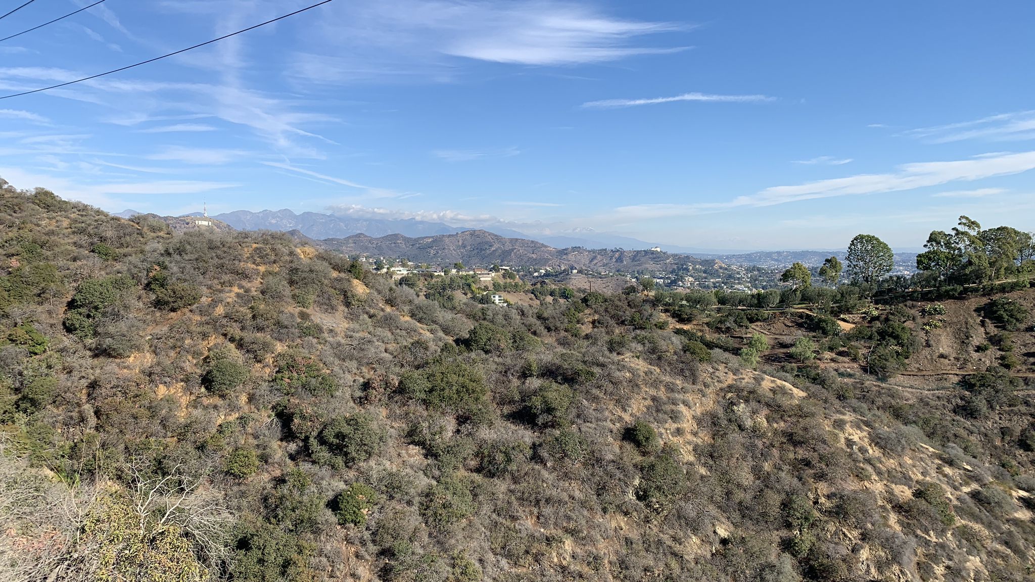 Brush-covered hillsides with distant mountains and a city under a blue sky. - Rock Mandala & West-Viewpoint – Runyon Canyon Park