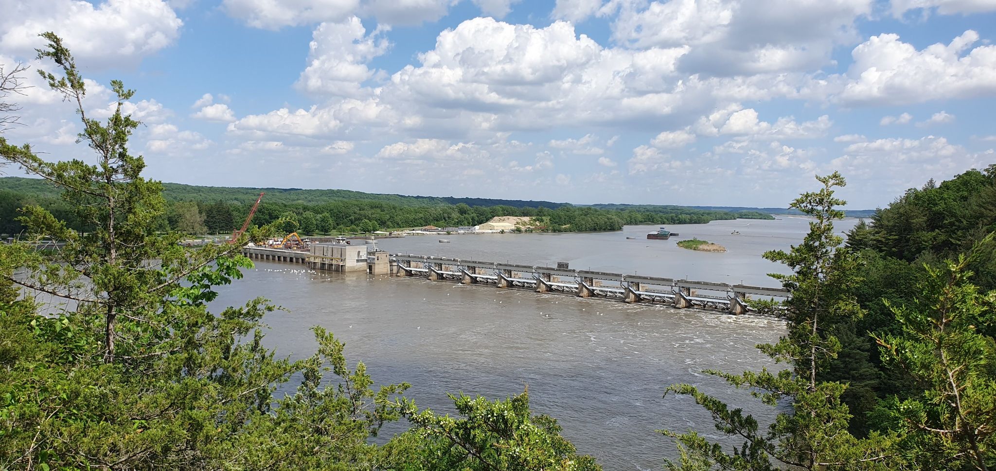 A dam spans a wide river, surrounded by green trees under a cloudy sky. - Starved Rock, Wildcat Canyon, and French Canyon Loop