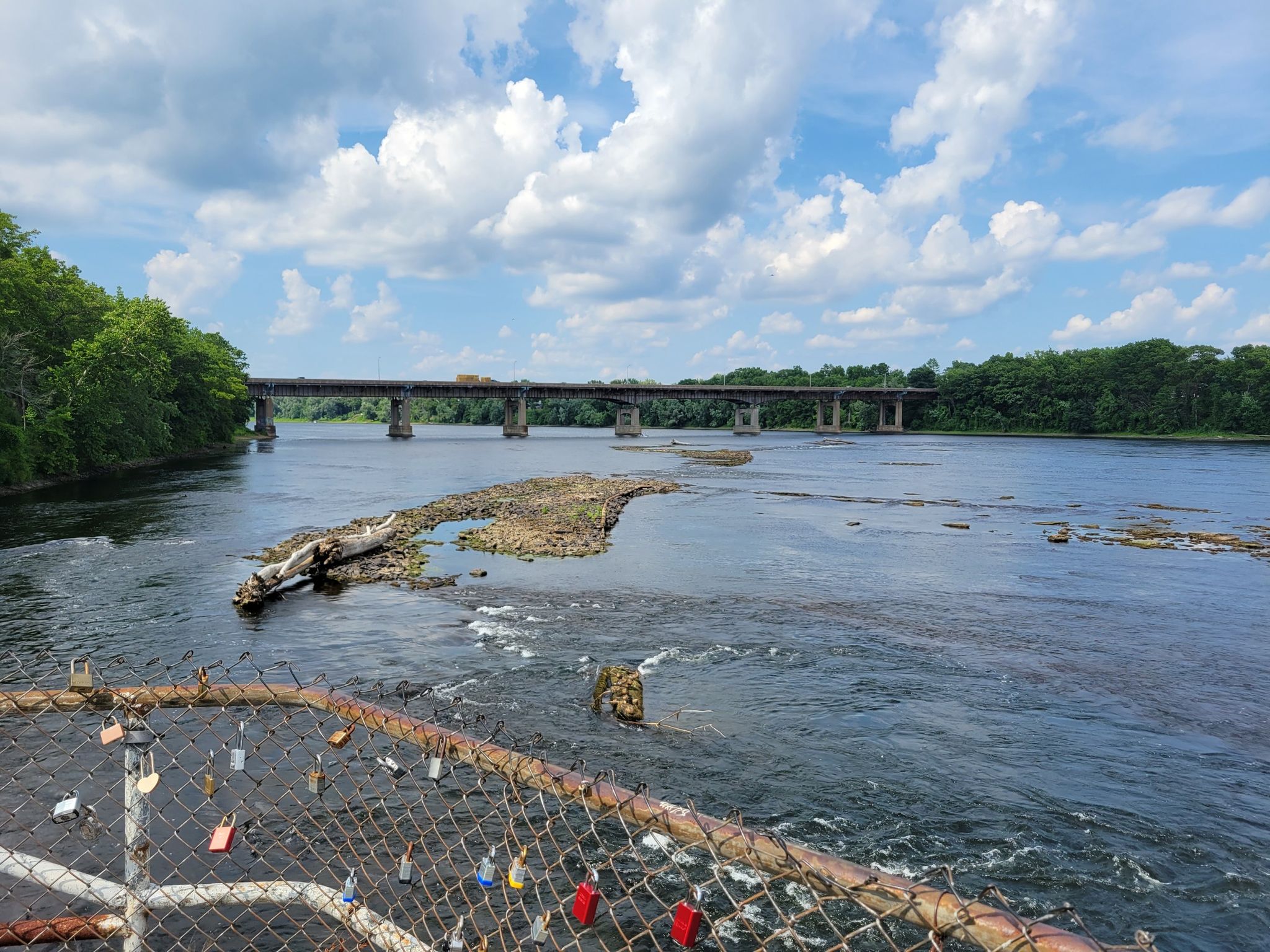 River with a distant bridge and a fence adorned with many locks. - Tinker Hill – Sherman Hill loop from East Forest Park