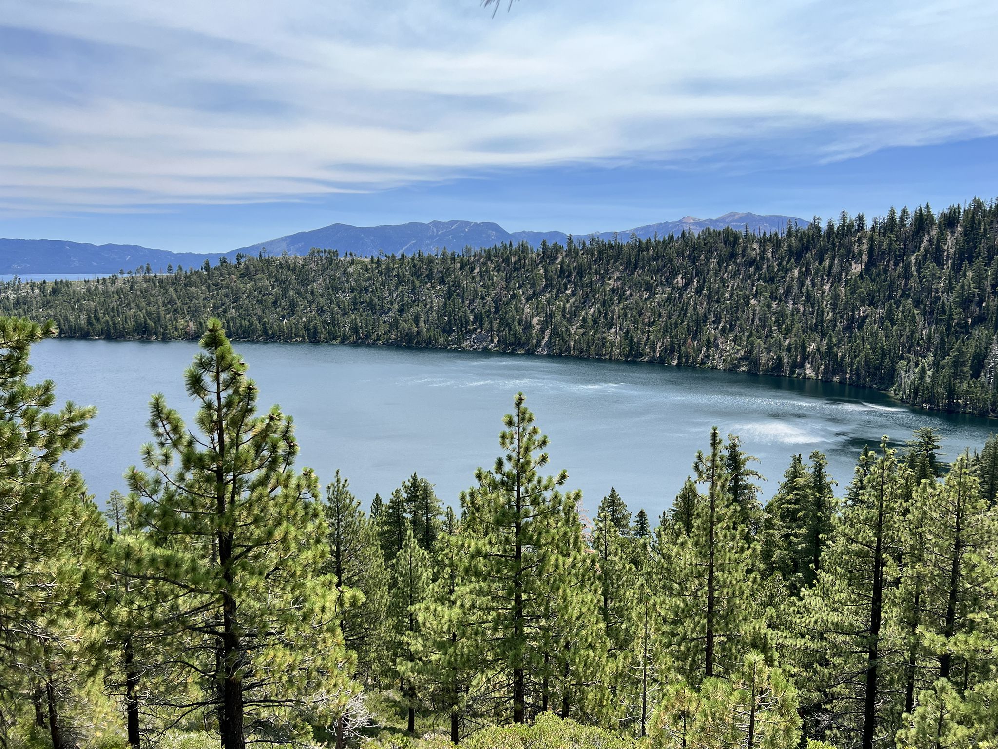 Lake surrounded by dense pine forest under a partly cloudy sky. - Cascade Falls Trail