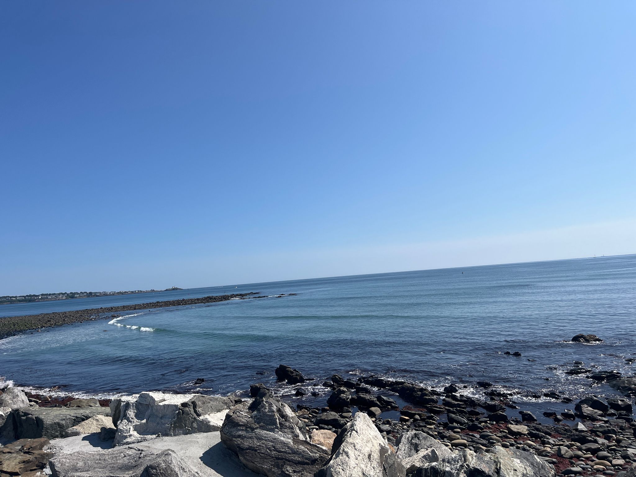 Expansive blue ocean meets a rocky shore under a clear sky. - Perkins Cove – Long Sands Beach loop from Somersworth