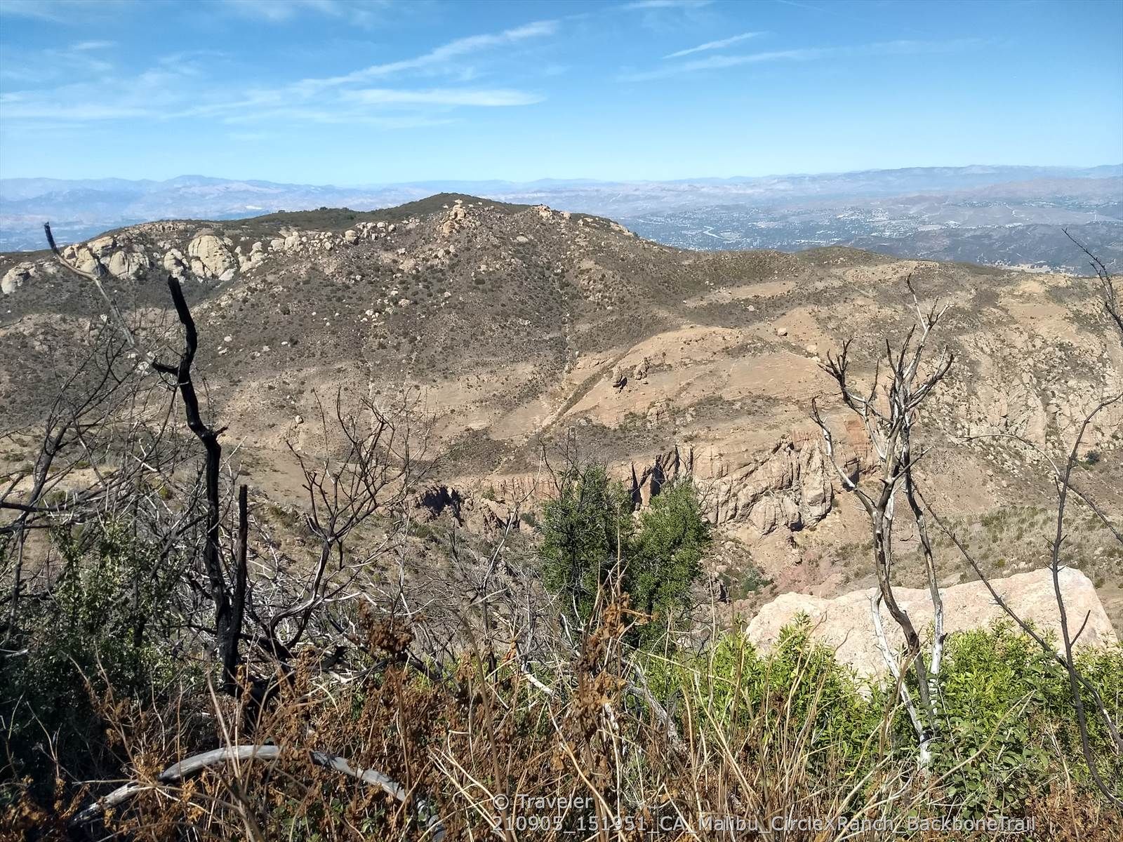 Dry, rocky hills and distant mountains seen through sparse, foreground brush. - Mishe Mokwa to Tri-Peaks and Sandstone Peak – Santa Monica Mountains National Recreation Area