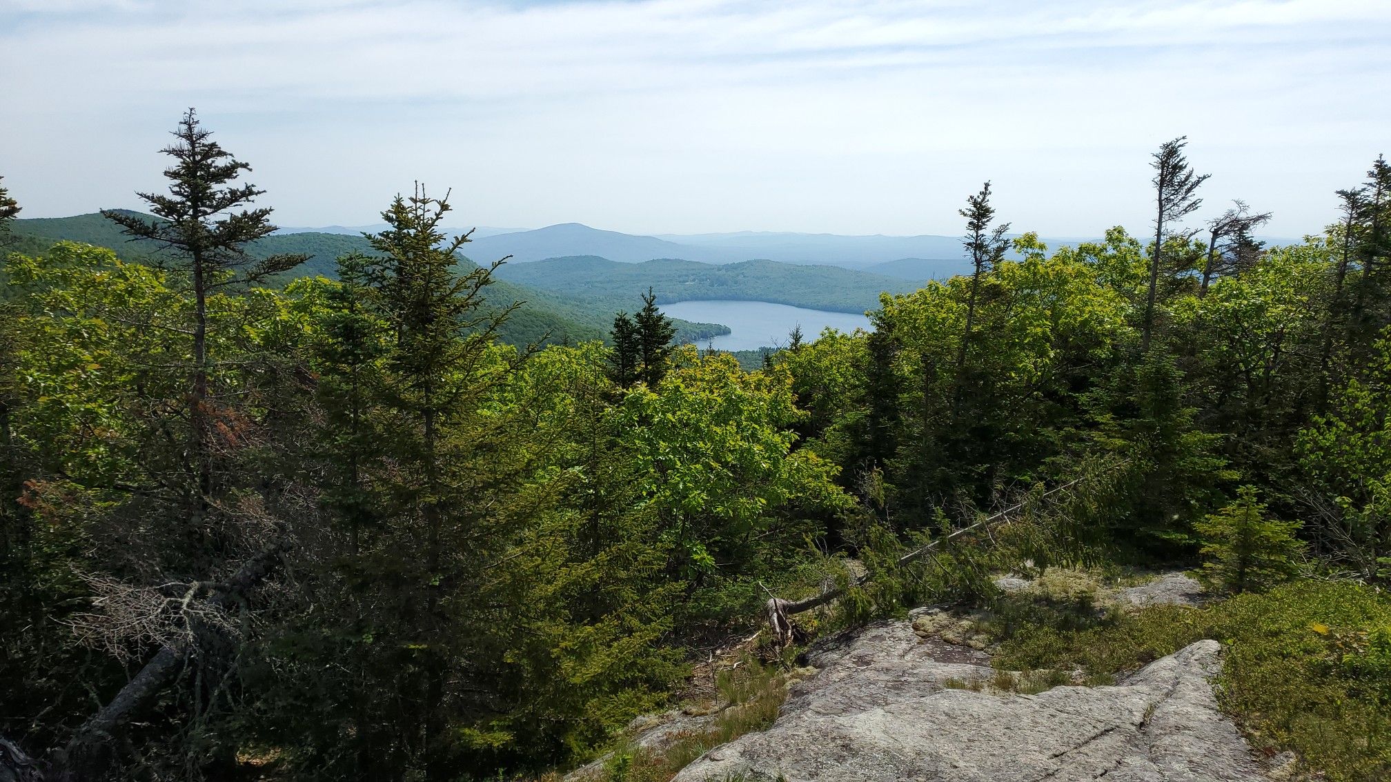Panoramic view of a lake nestled among green forests and distant mountains. - Big Ball Mountain via Italian Trail