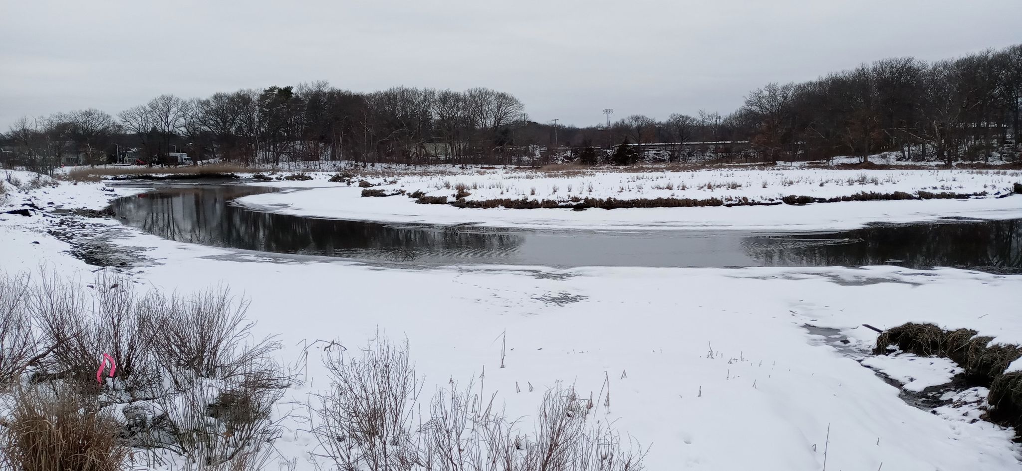 Overcast winter scene of a winding river through snow-covered banks and trees. - Wollaston Beach Promenade – Furnace Brook Parkway loop from Squantum Point Park