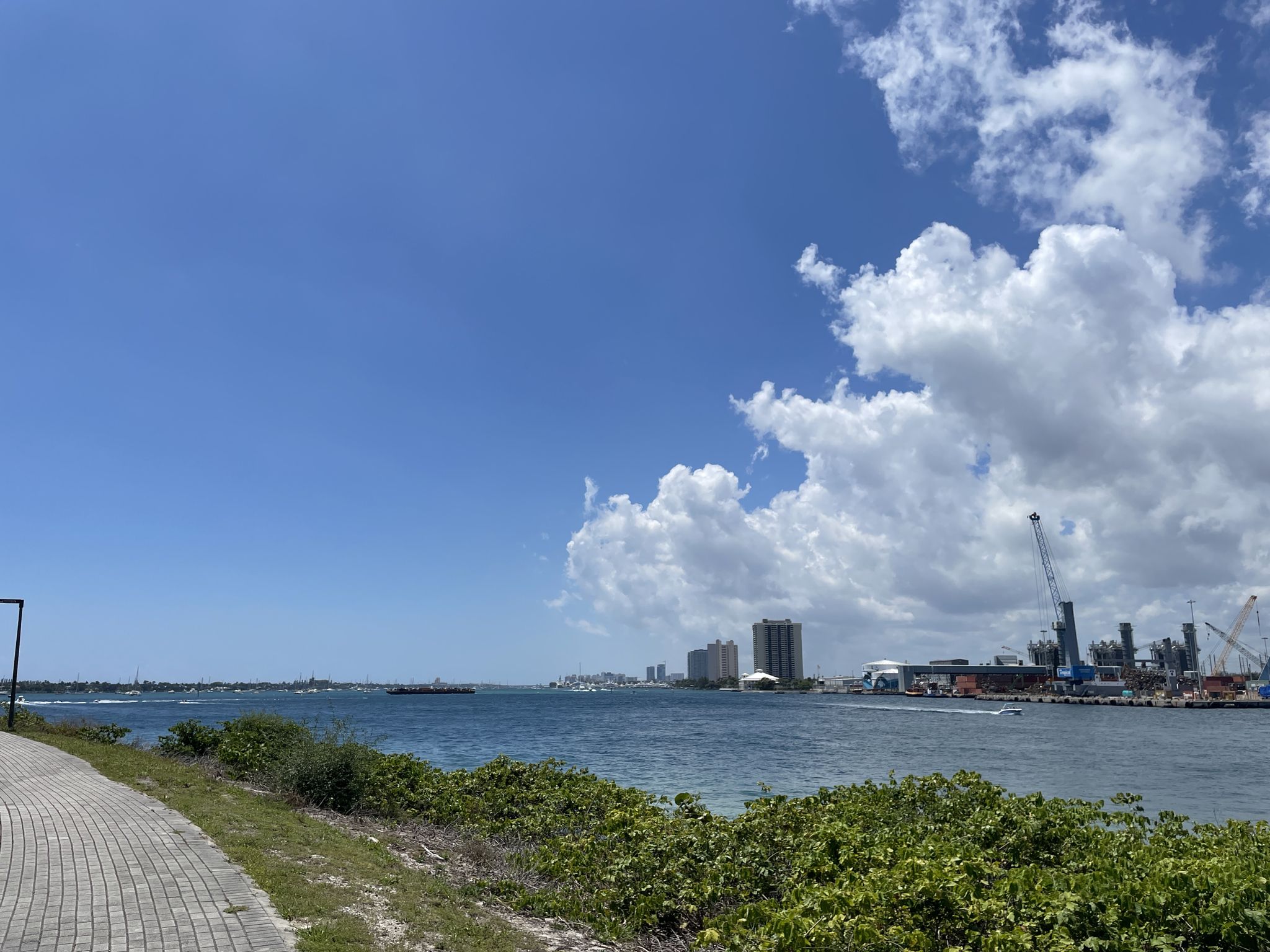 Expansive water view with a distant city skyline and industrial port. - Peanuts Island Park loop