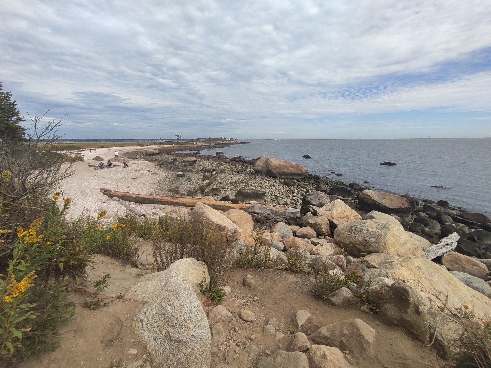 Rocky and sandy coastline with calm ocean under an overcast sky. - Hammonasset Beach State Park