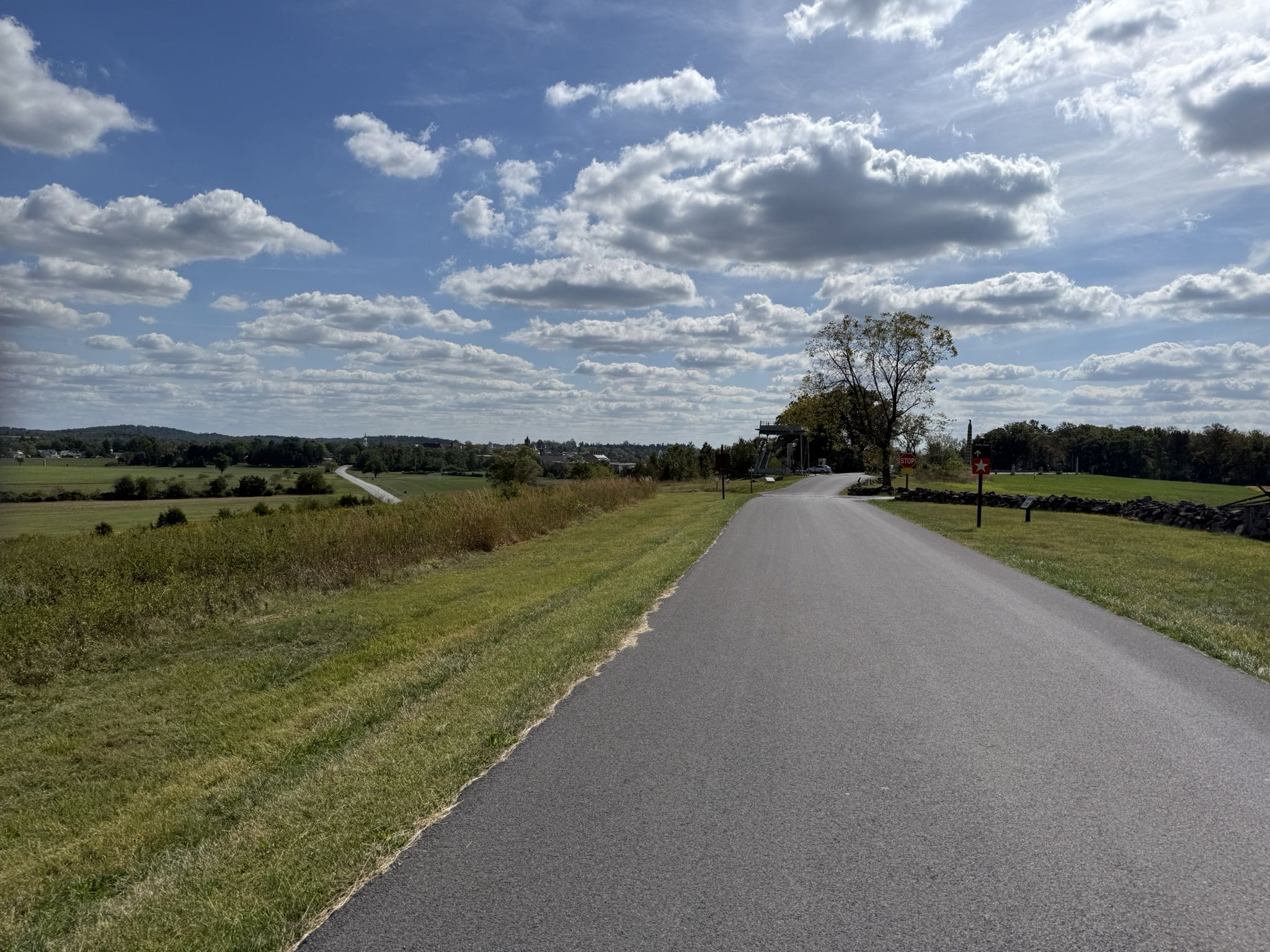 Winding paved road through green fields under a bright, cloudy sky. - The apple orchards & York Springs loop from Gettysburg