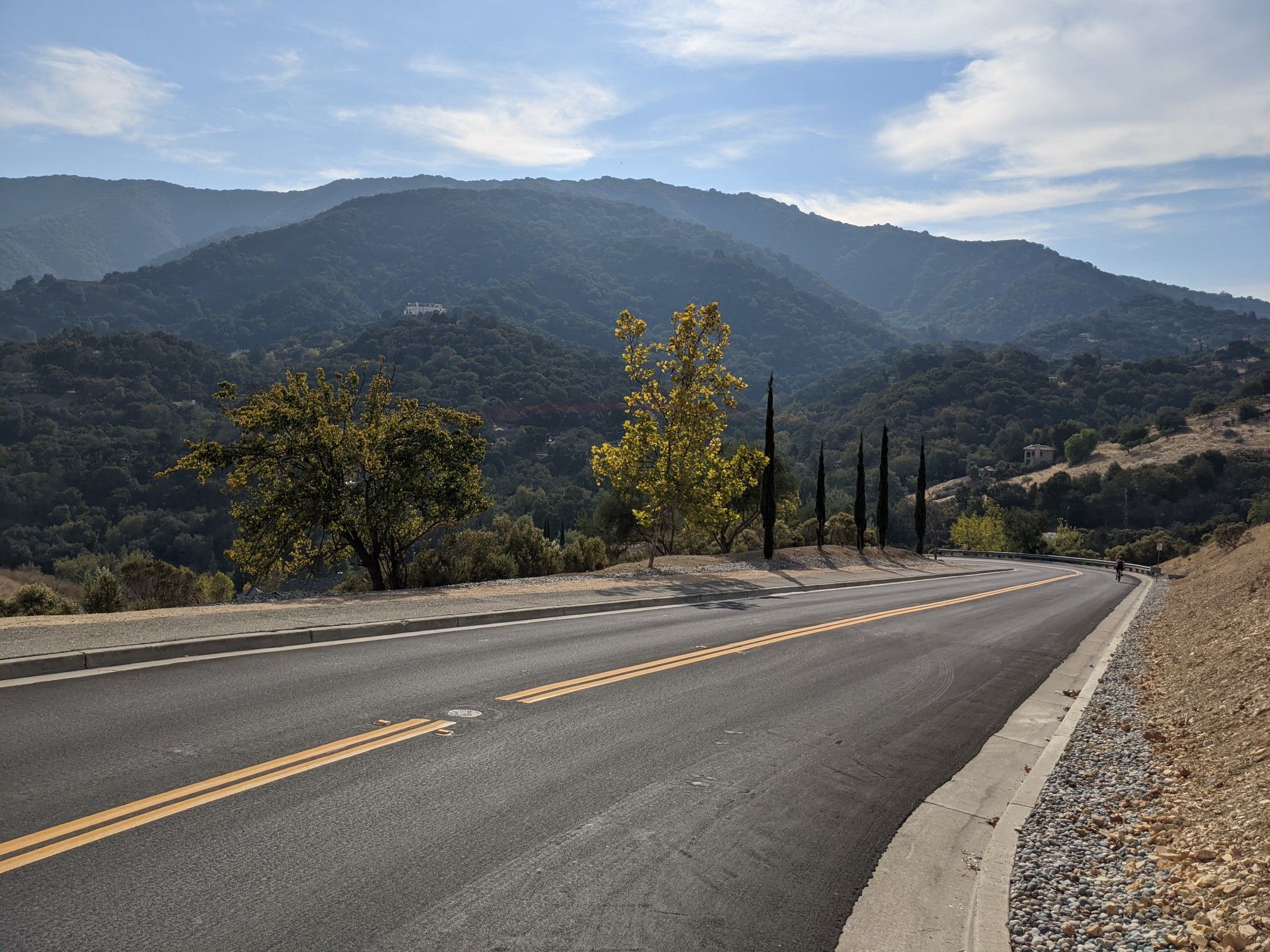 Winding road through green hills under a bright, partly cloudy sky. - Santa Rosa and Ridge Trail Loop