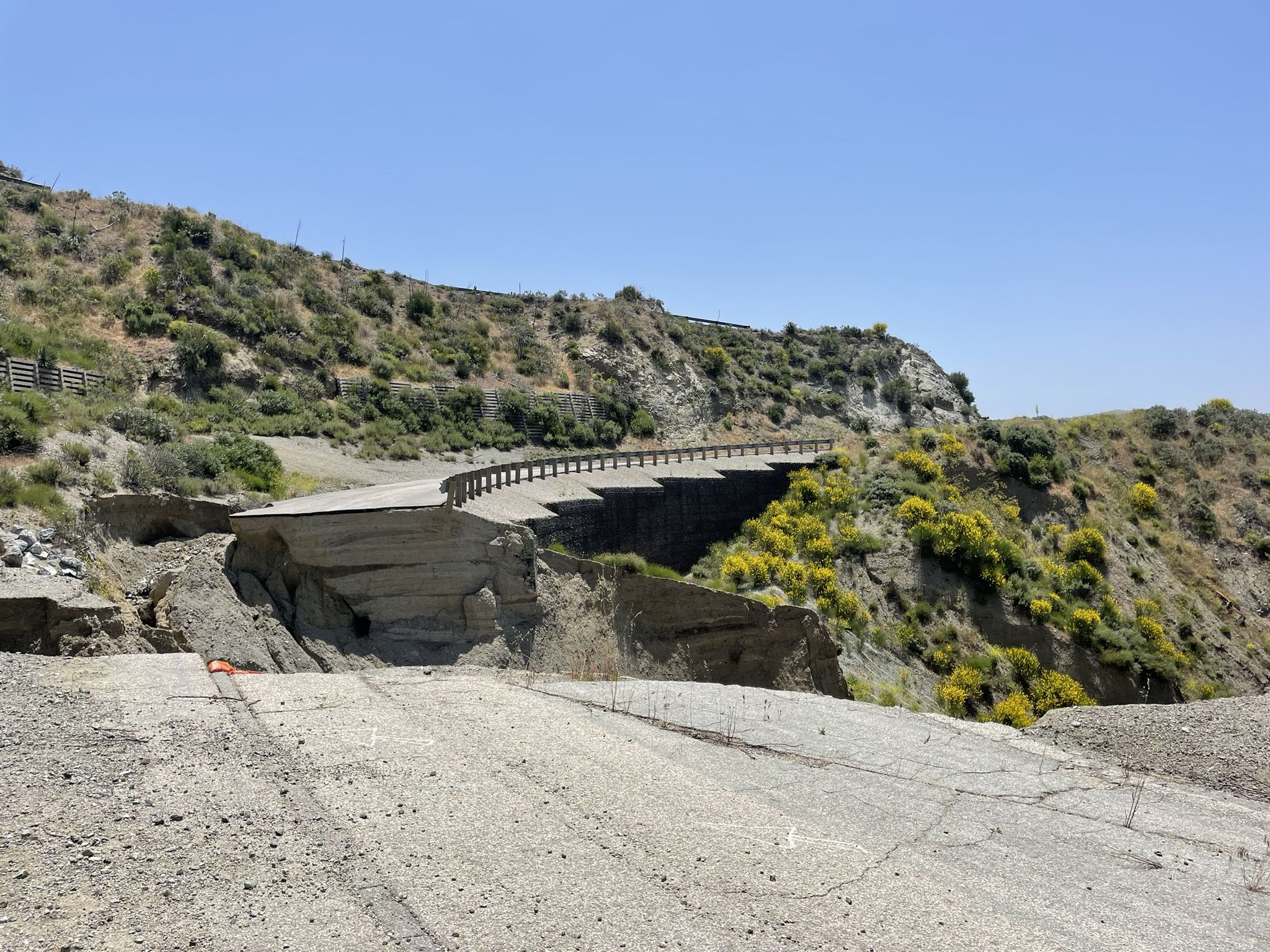 Collapsed road section on a dry, brushy hillside under clear daylight. - Santa Clara Truck Trail and Dagger Flat Loop