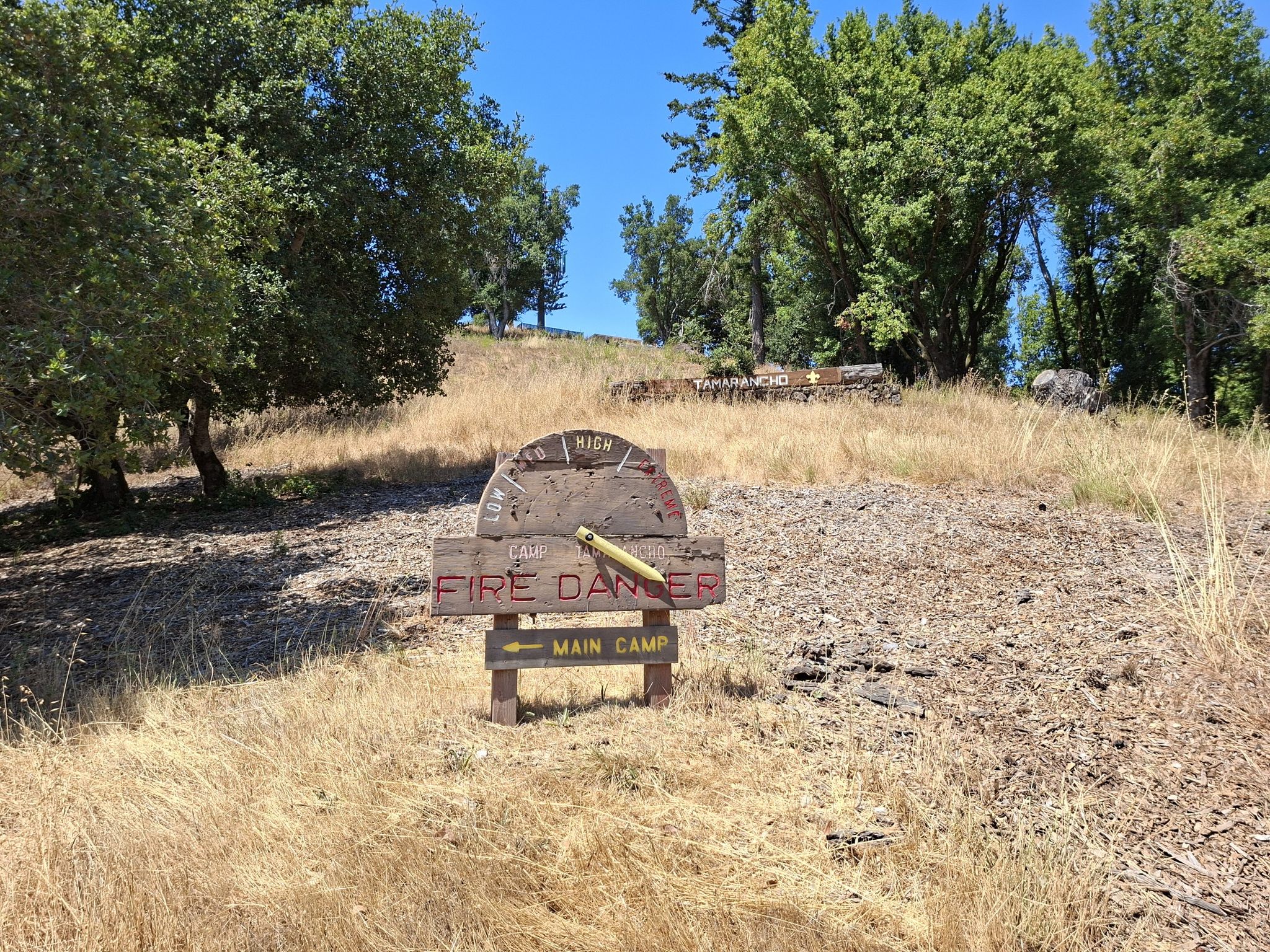 A wooden fire danger sign in a dry grassy field on a sunny day. - Camp Tamarancho Trailhead – B-17 crash site loop from Fairfax