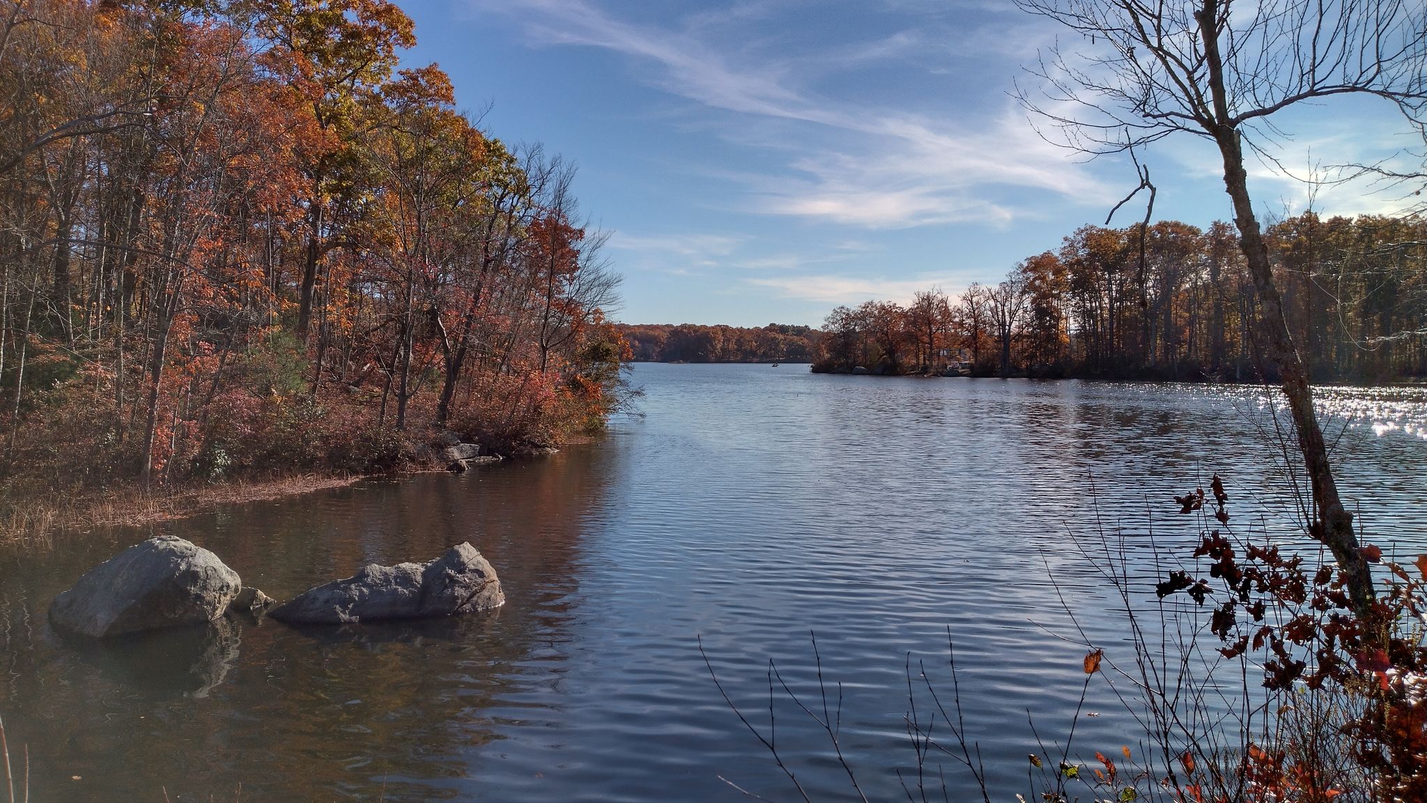 Sunny autumn day over a calm lake surrounded by colorful trees. - Les Pawson Trail loop