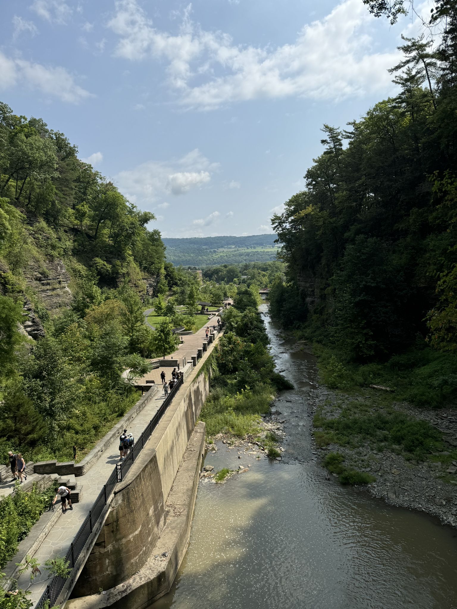 Sunny day with many people walking on a paved path beside a river in a gorge. - Gorge and Indian Trail Loop