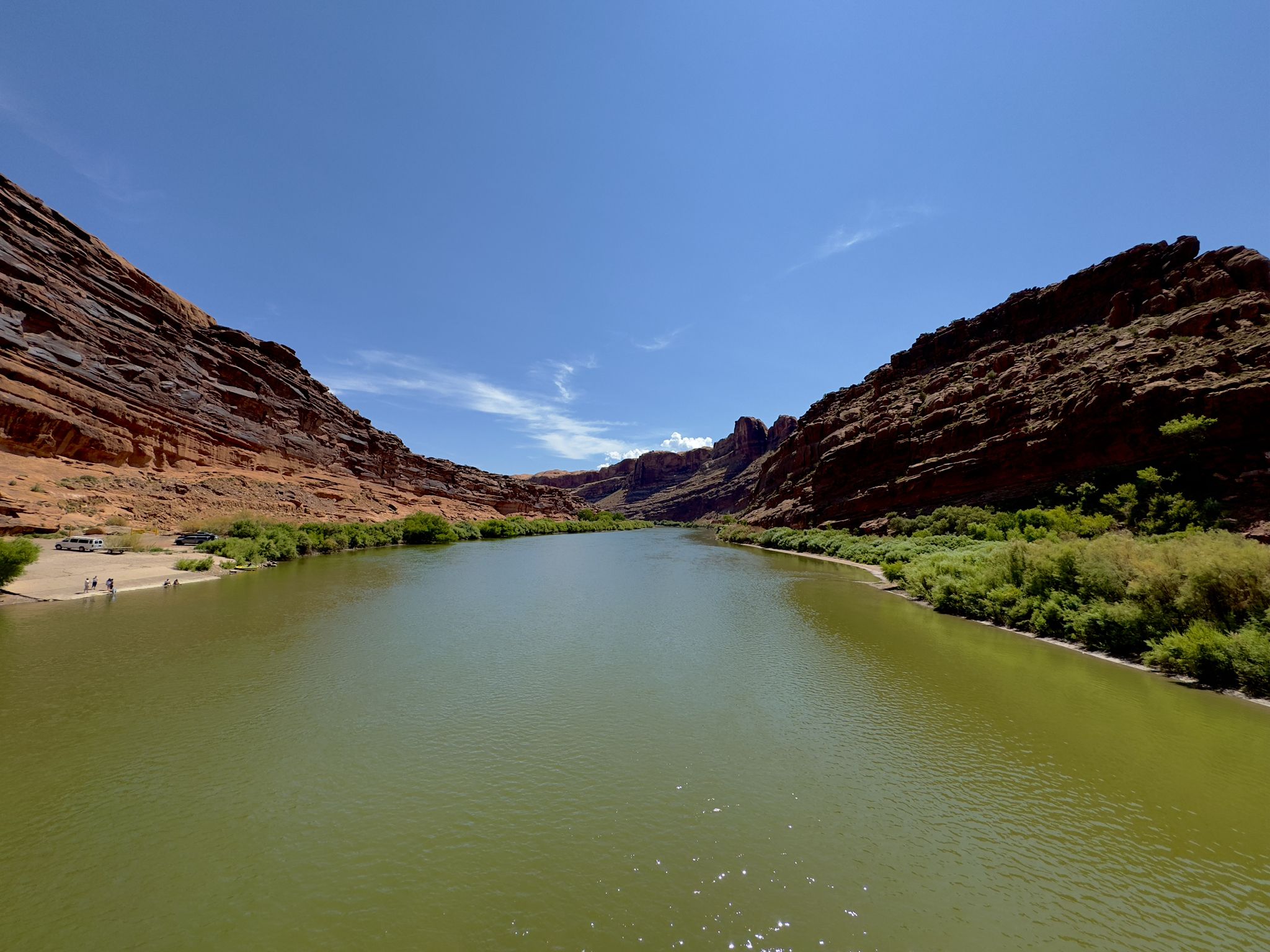 Wide green river between towering red rock canyon walls, bright day. - Mural "The Delicate Arch" – Bridge over the Colorado River loop from Moab