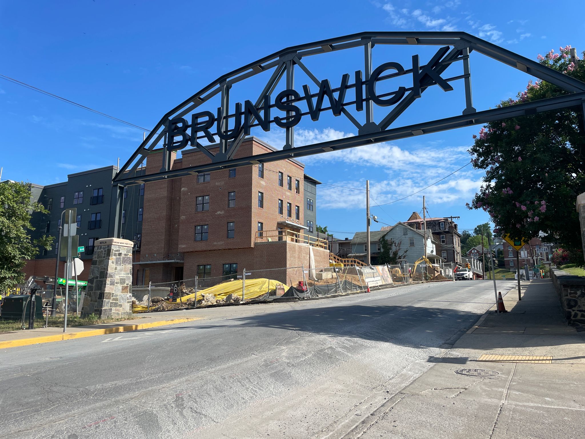A large metal archway spans a street with buildings under construction. - Brunswick – Beach access loop from Brunswick