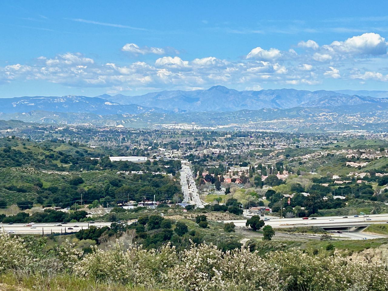 Expansive valley view with a city, highway, and mountains under a bright sky. - Elsmere Canyon Road Loop