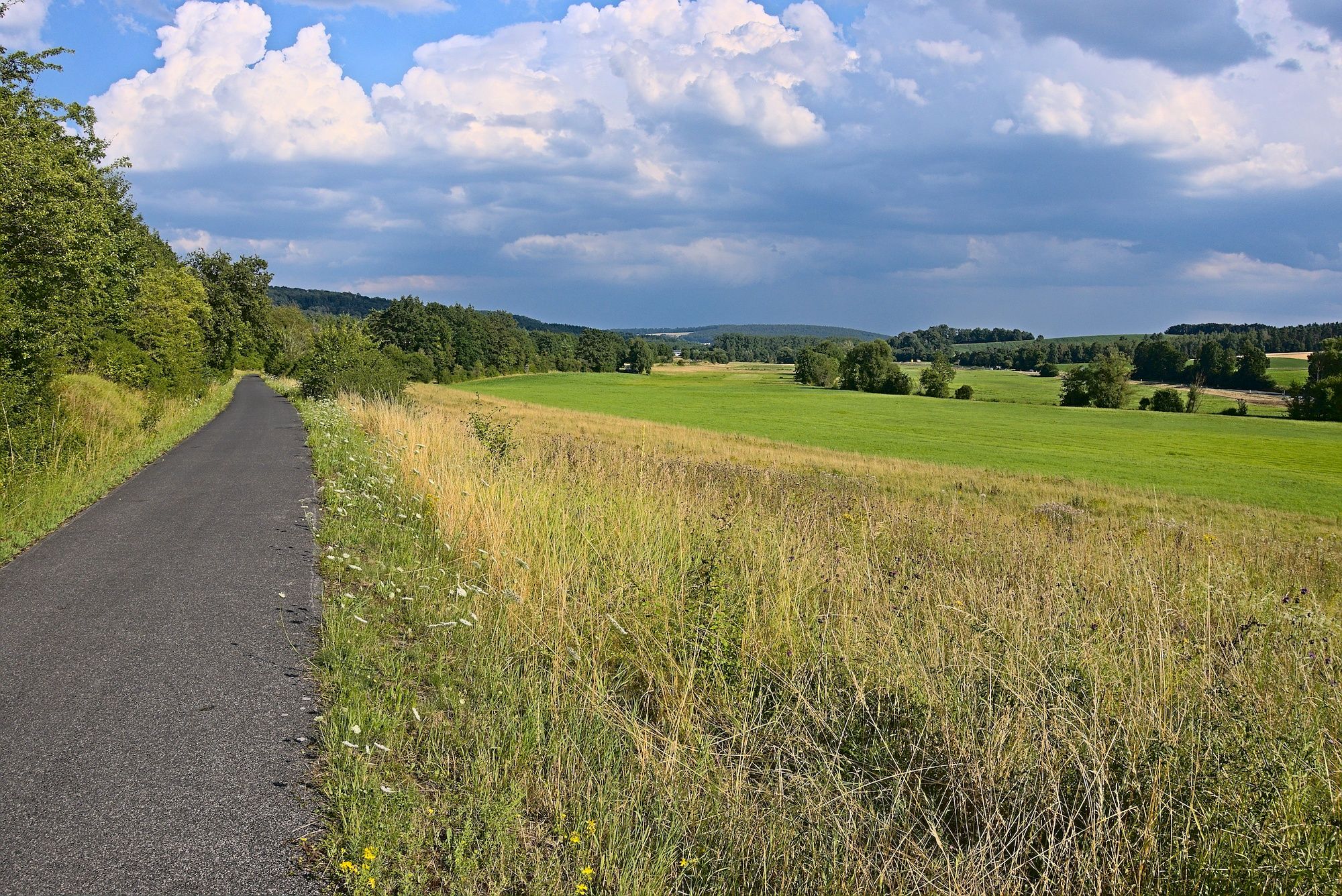Rückkehr auf der ehemaligen Bahntrasse nach Ebern, wo sich bereits ein kräftiger Regenguss ankündigt