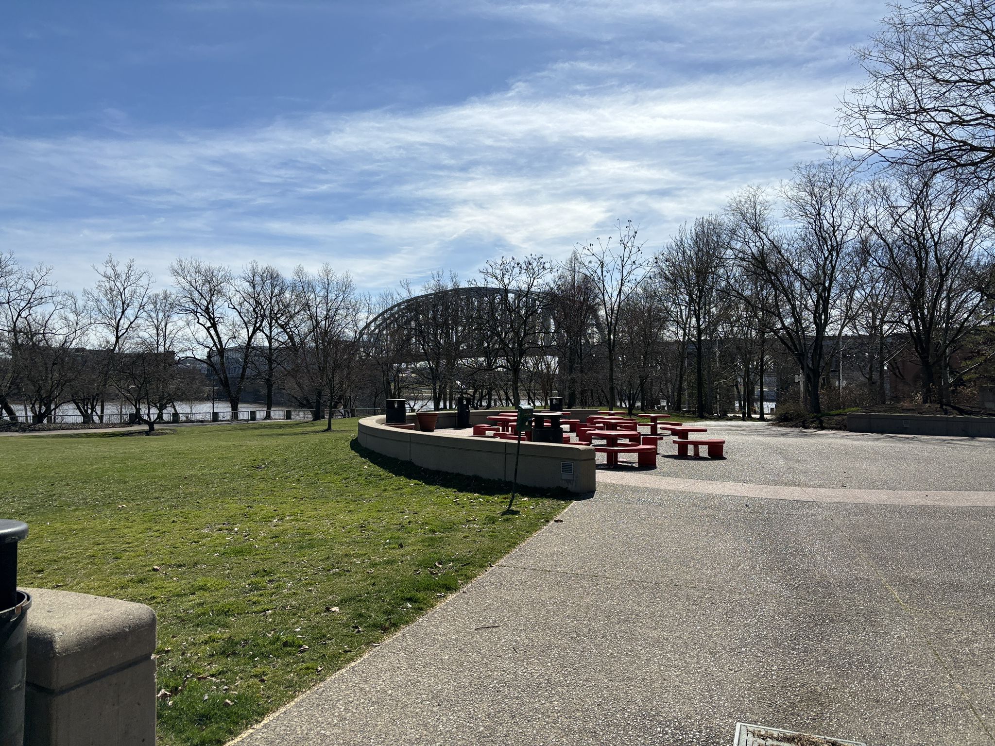 Grassy park with red picnic tables, trees, and a bridge in distance. - Serpentine Wall – Cincinnati Flying Pig Statues loop from Cincinnati