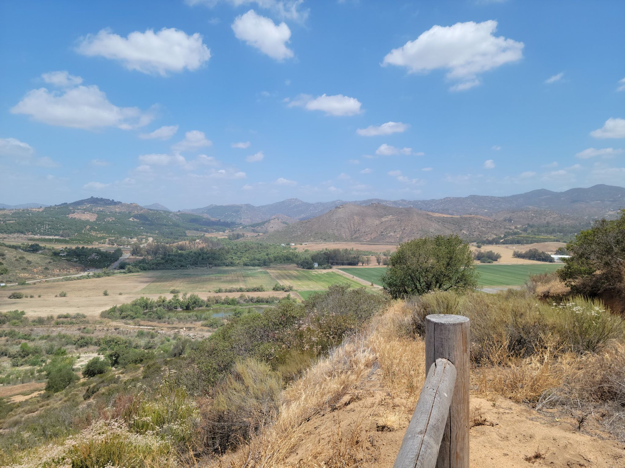 Sunny valley view with green fields, distant mountains, and blue sky. - Mule Hill – Mule Hill Trailhead loop from West Bernardo Drive & Duenda Road