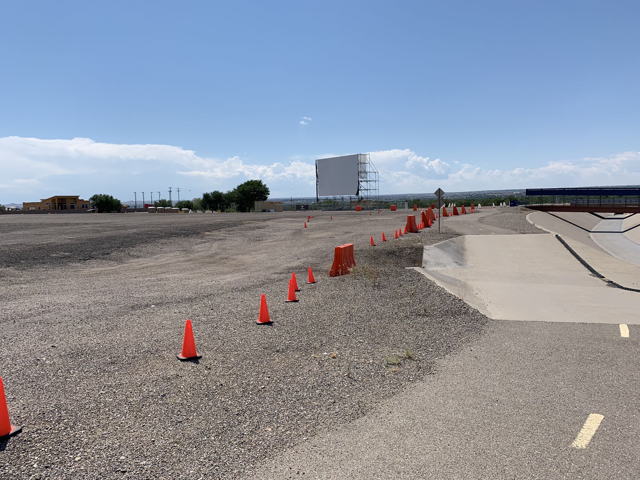 Empty gravel lot with orange cones leading to a large outdoor screen. - Northern Diversion Trail and Balloon Fiesta Park Loop