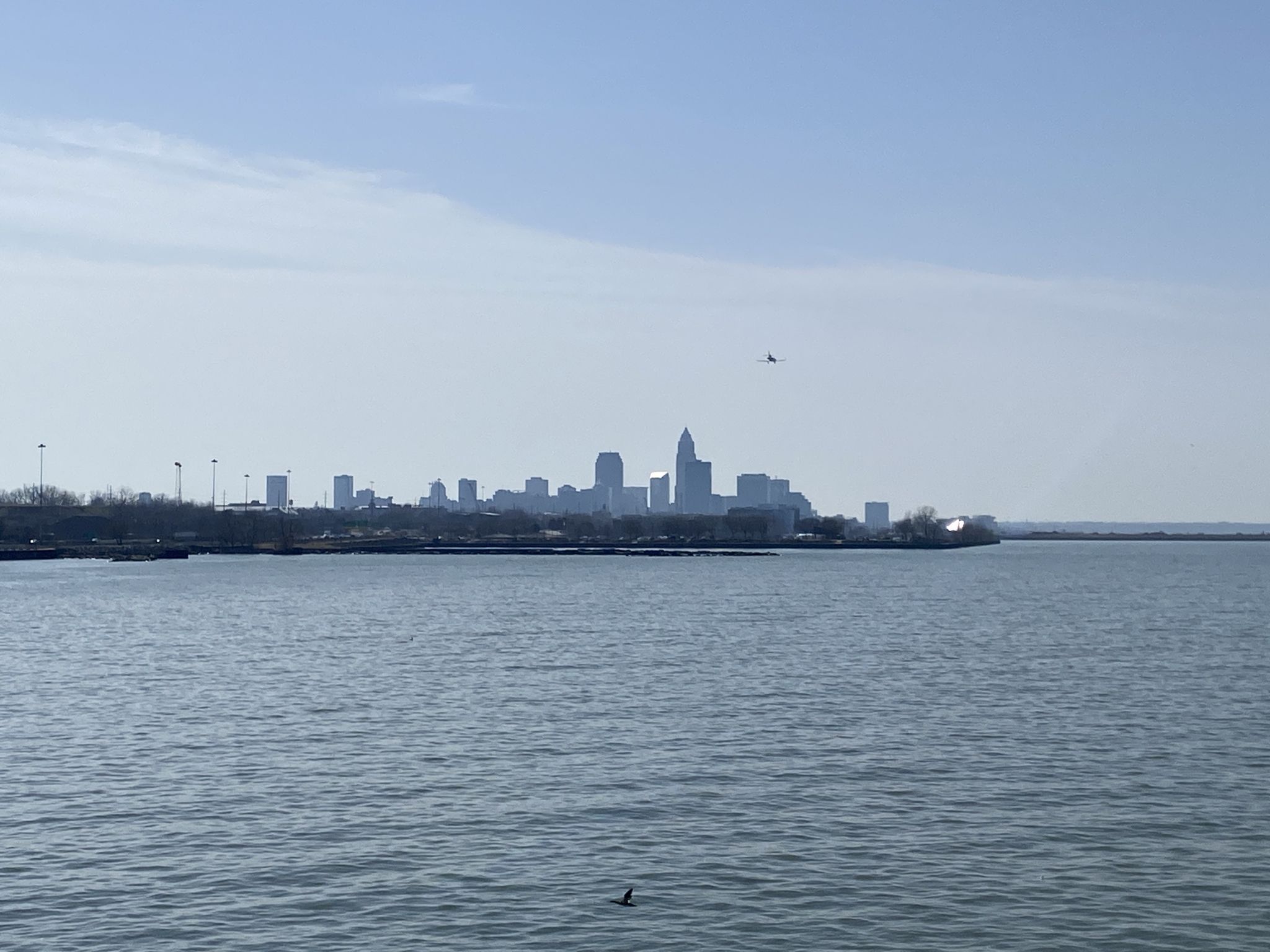 Distant city skyline across water with a helicopter in a hazy sky. - Perimeter Loop Trail