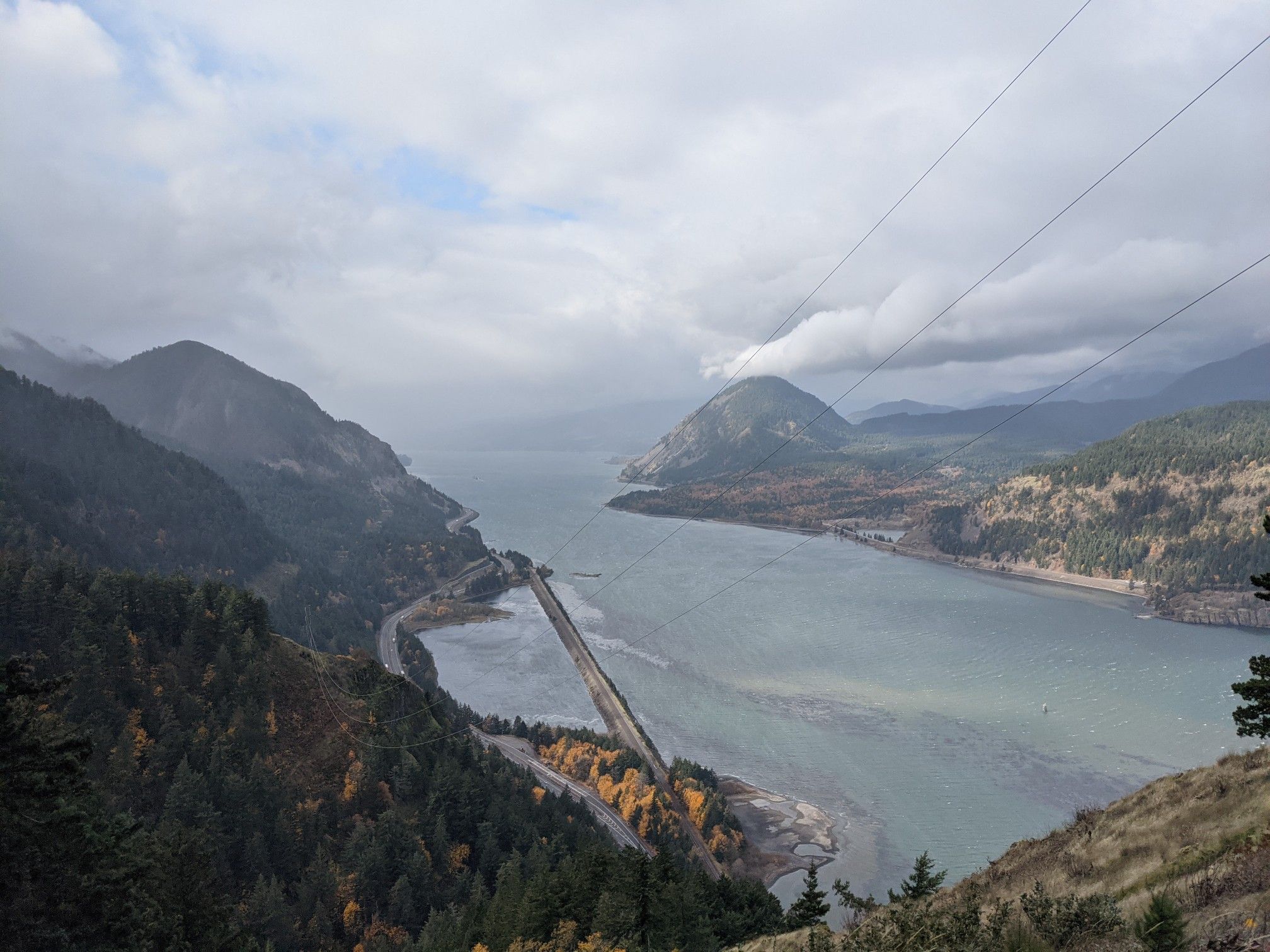 Overcast view of a wide river winding through forested mountains with roads. - Mount Defiance Trail — Columbia River Gorge