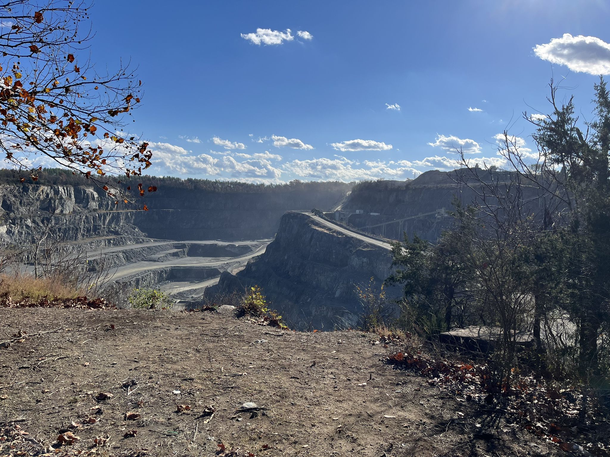 A vast, tiered quarry landscape under a bright, sunny blue sky. - Trailside Park – Luck Stone Quarry Overlook loop from Ashburn