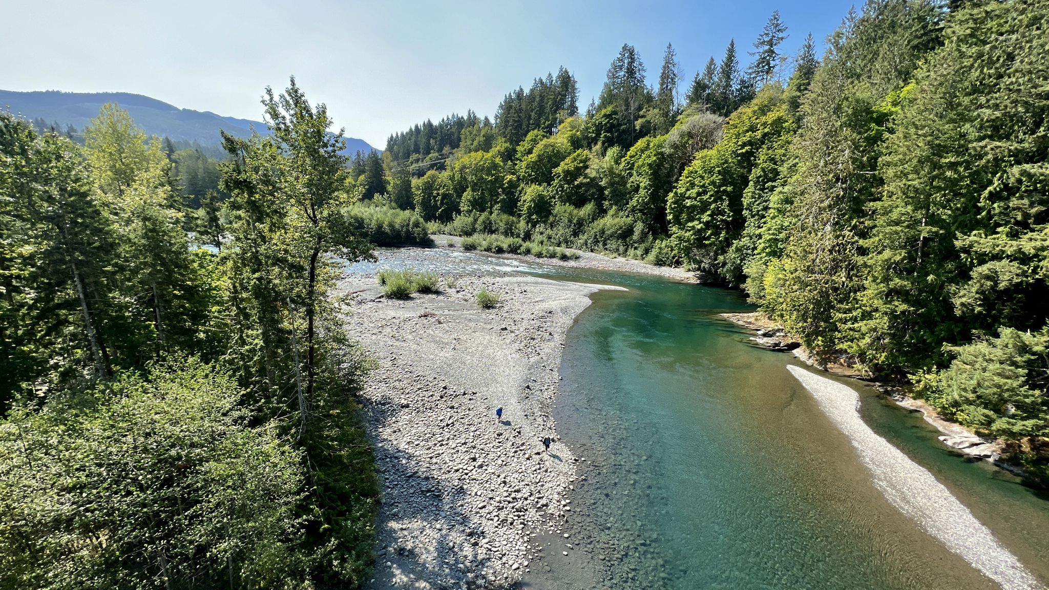 A clear blue-green river flows through a forested valley on a sunny day. - Port Angeles to Lake Crescent