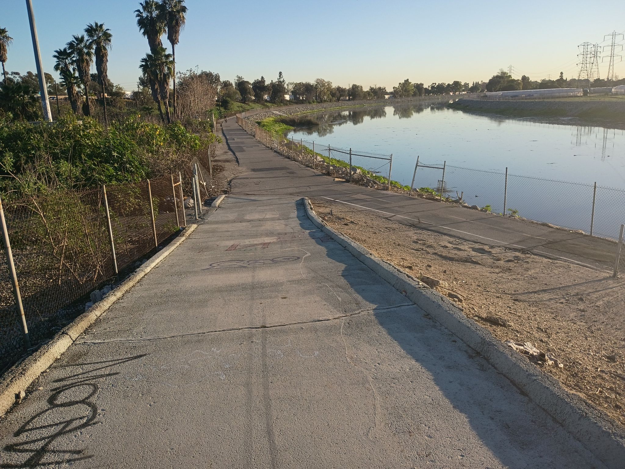 Paved path next to a calm river with palm trees at sunset. - Rio Hondo Bike Bridge – Bosque del Rio Hondo loop from Lynwood
