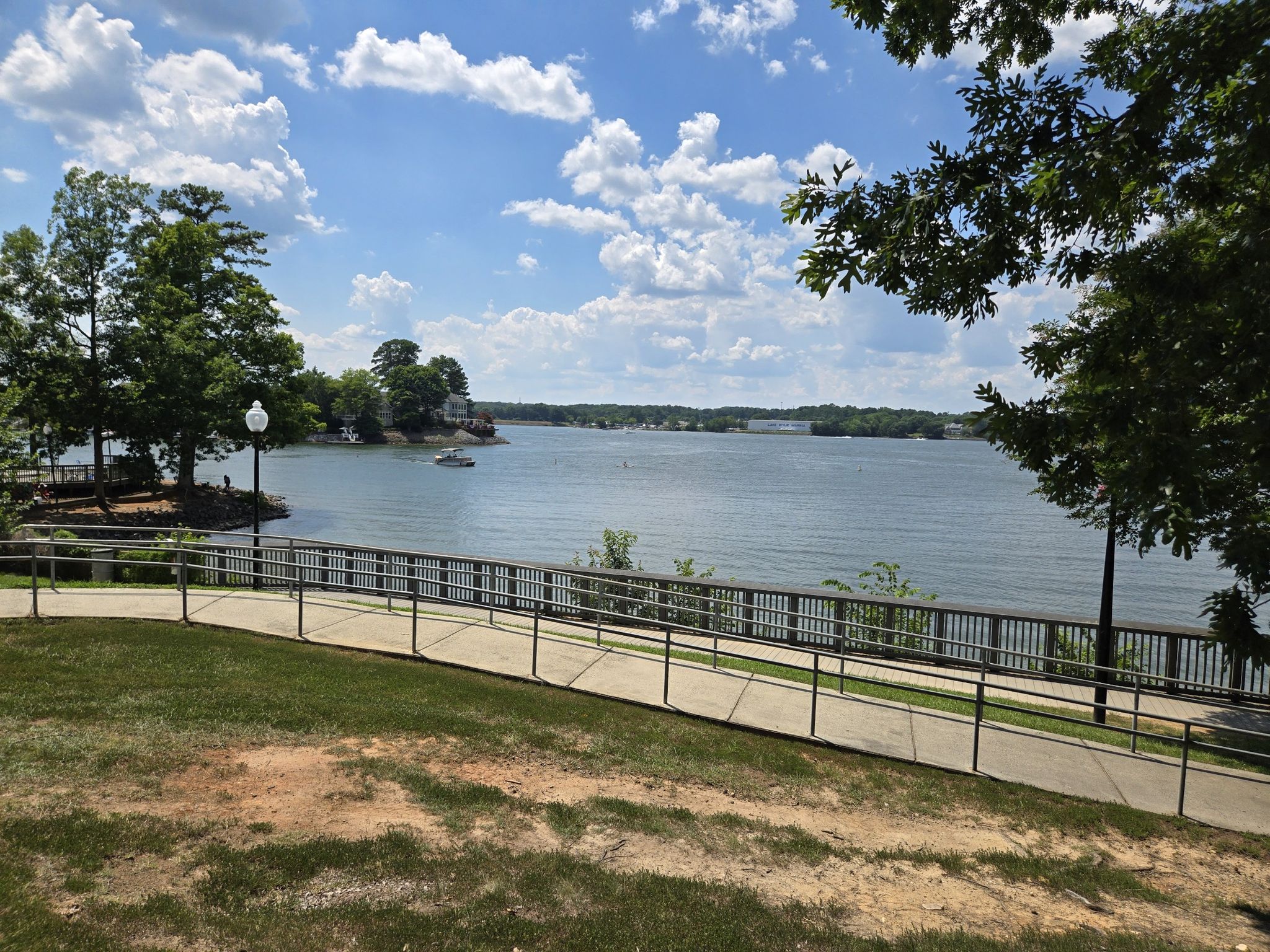 Sunny view of a wide lake with distant shore, framed by green trees. - McDowell Chestnut Loop