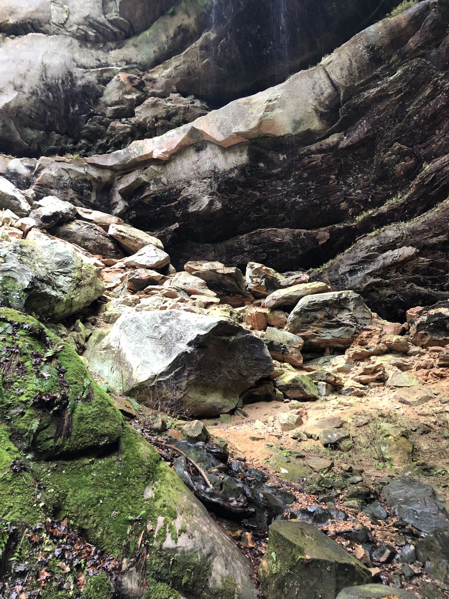 Rocky, mossy cave interior with large boulders and dark crevices. - Gray's Arch Loop
