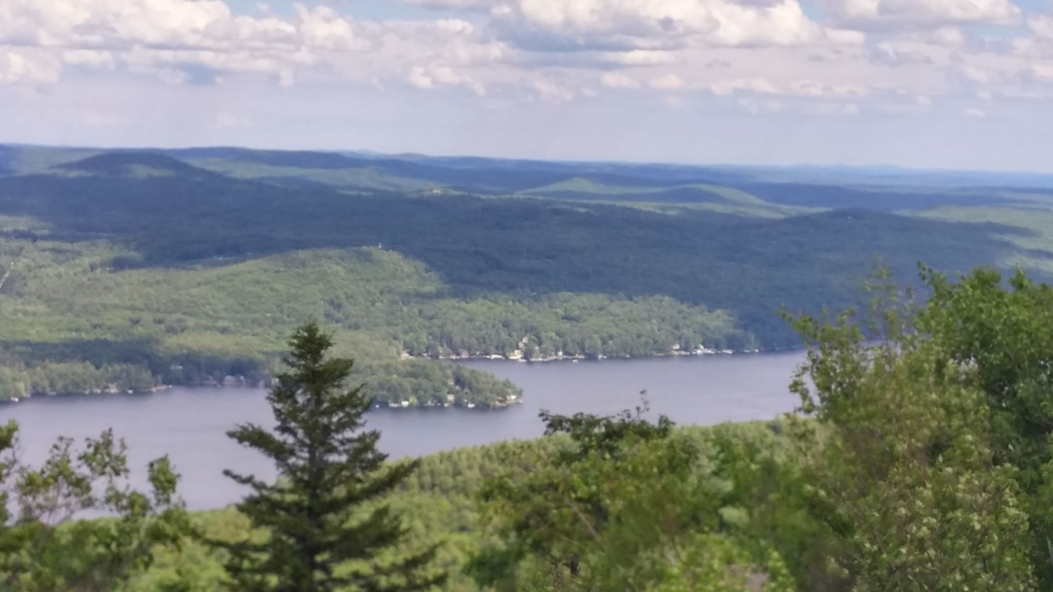 Scenic view of a calm lake surrounded by green forests and distant hills. - Mount Major via Jesus Valley - Beaver Pond Trail