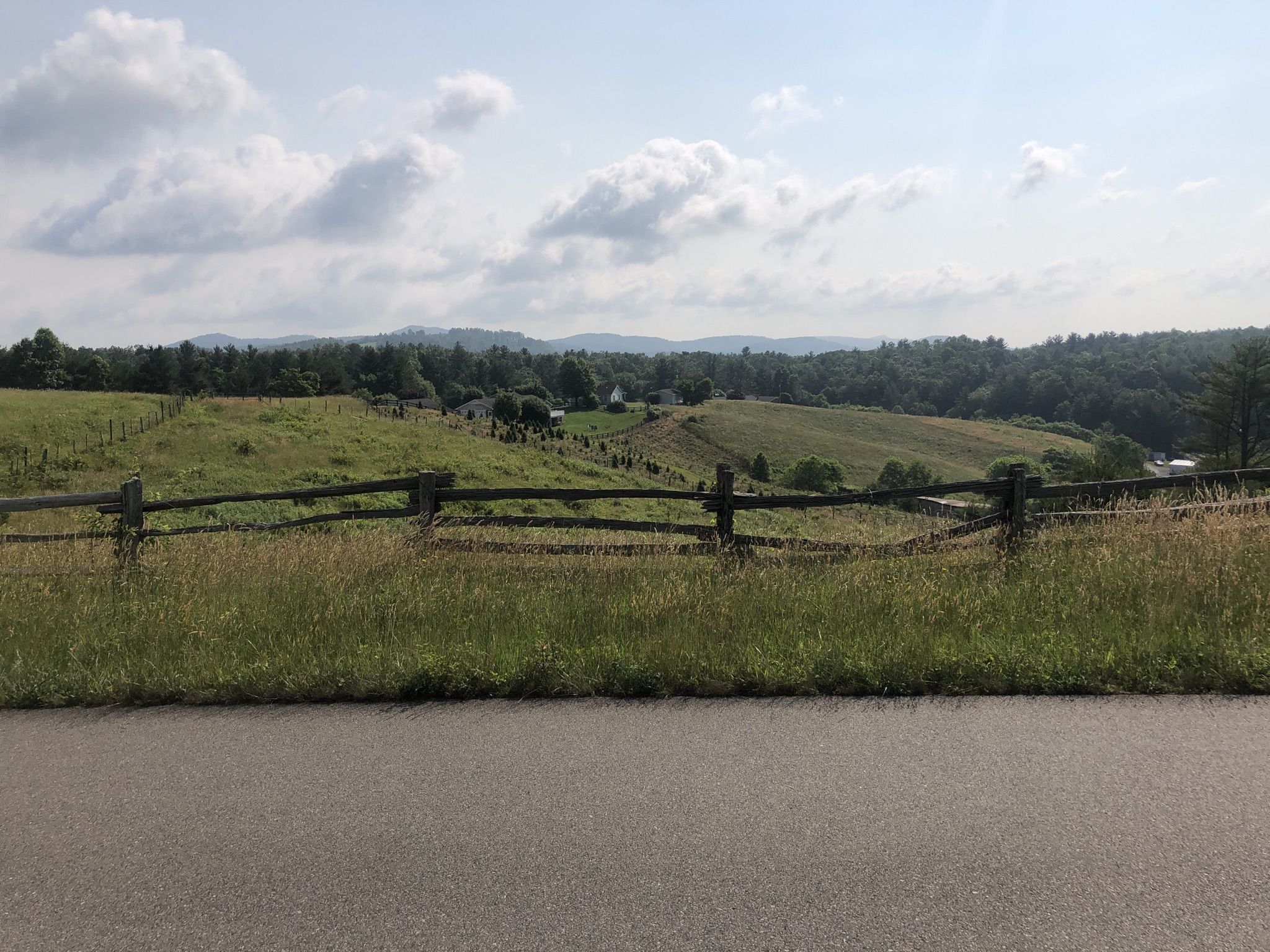 Rural landscape with a wooden fence, green fields, and distant hills. - Jumpinoff Rock Overlook Trail loop from Jefferson