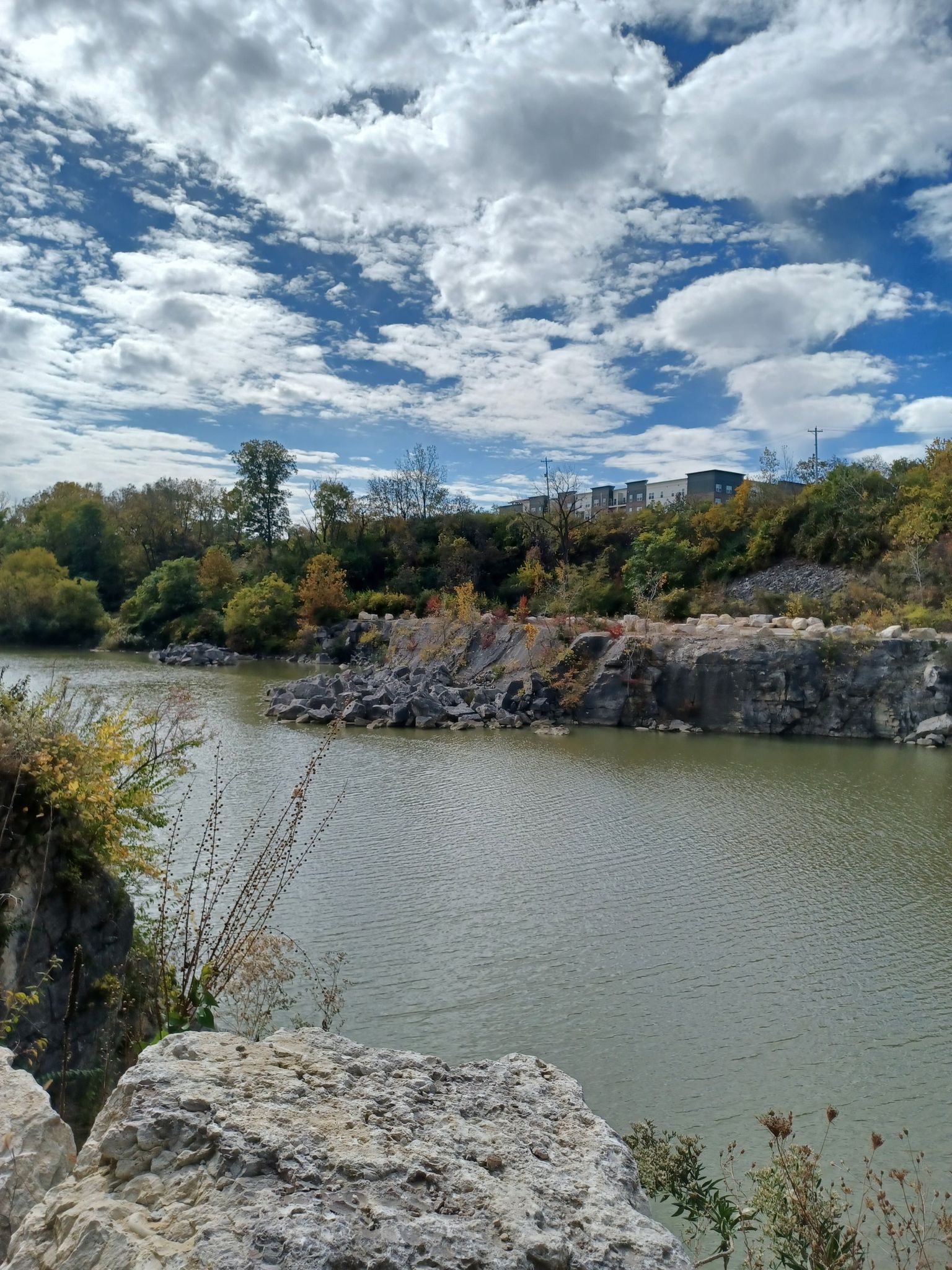 River with rocky banks, autumn trees, and a partly cloudy sky. - Roberts Millikin Ditch loop from Quarry Trails Metro Park