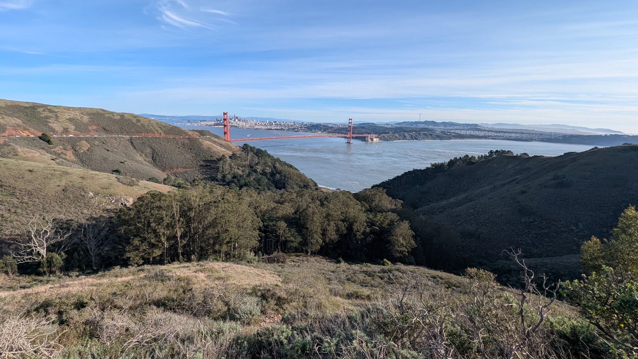 Red suspension bridge spans a wide bay between green hills under a clear sky. - Conzelman Road loop from Sausalito